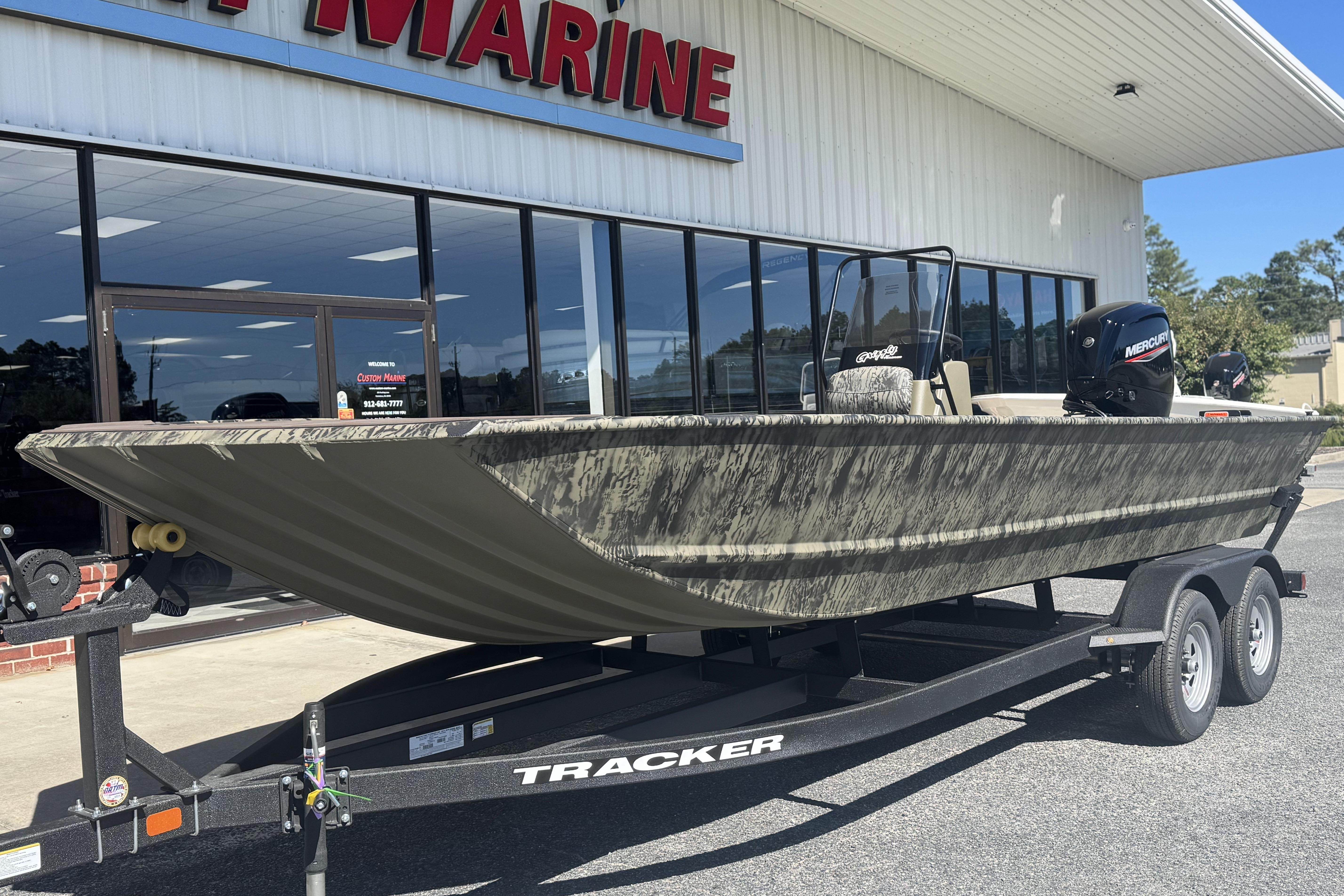 2026 Tracker Grizzly 2072 CC boat on trailer outside marine store.