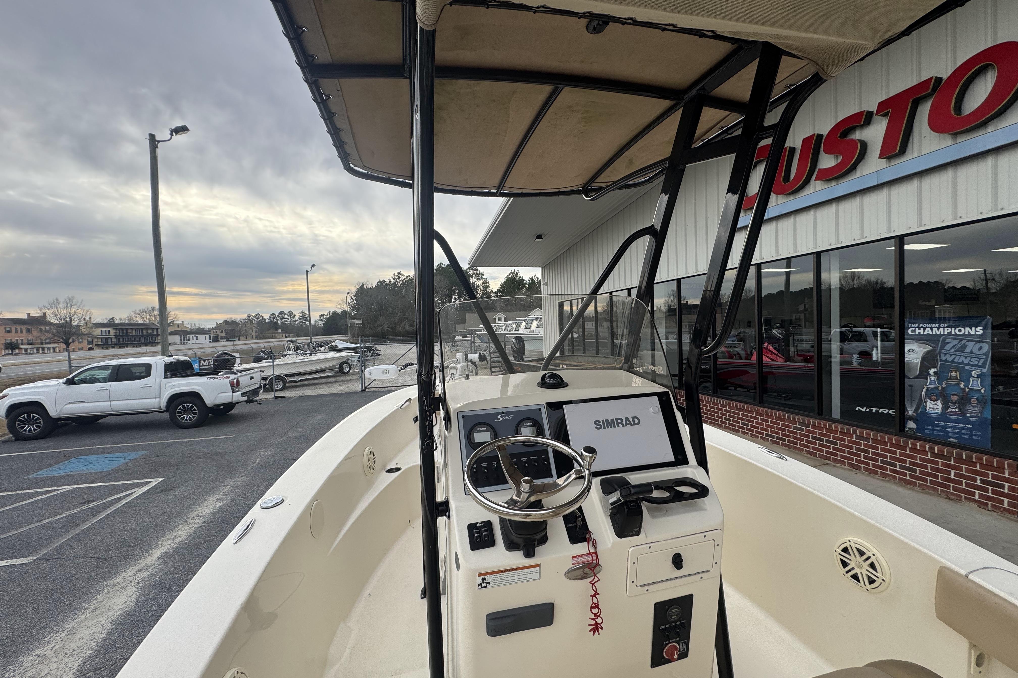 2020 Scout 195 Sportfish boat with steering console, parked outside dealership.