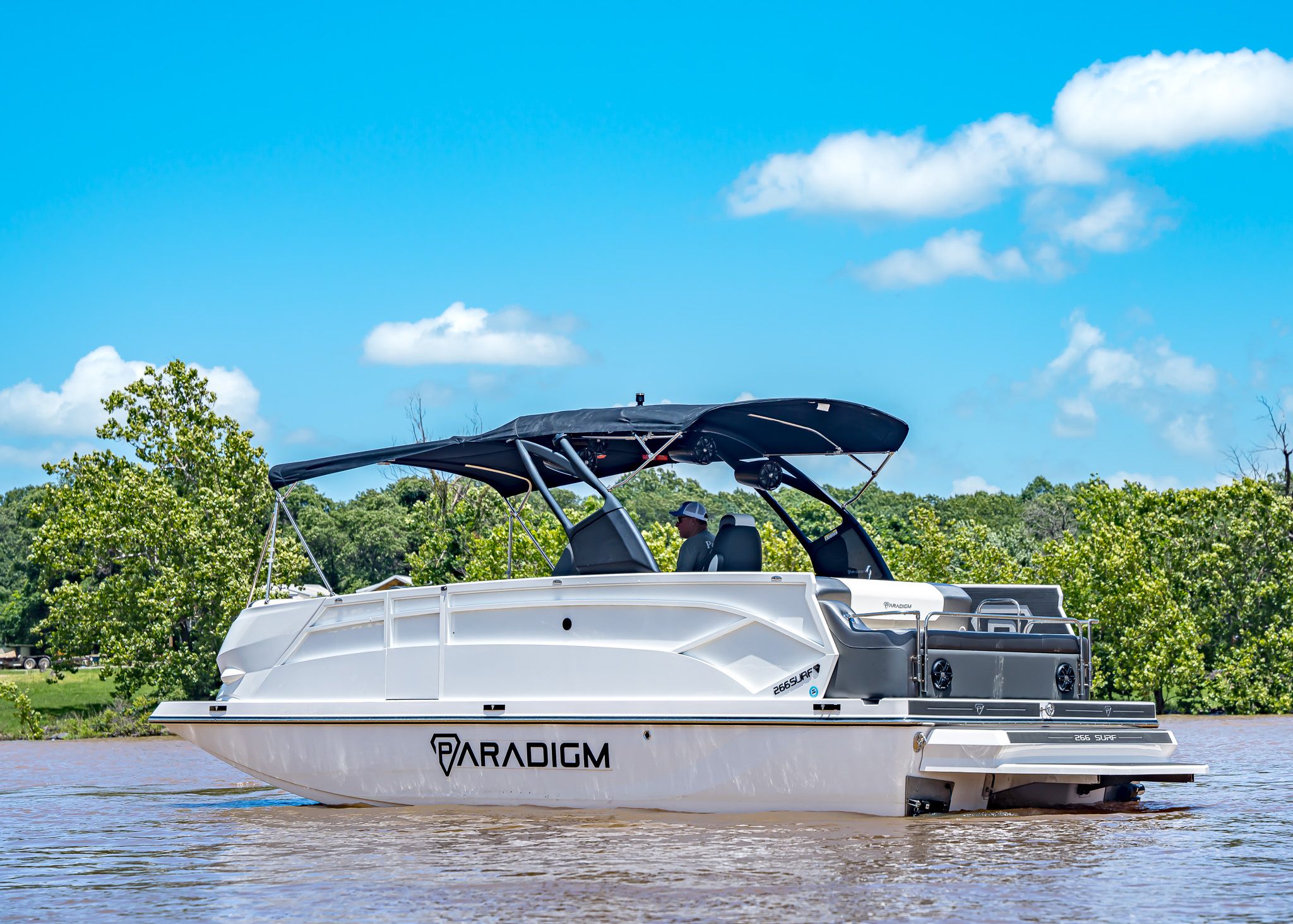 2025 Paradigm 266 SL SURF boat on a river under sunny skies.