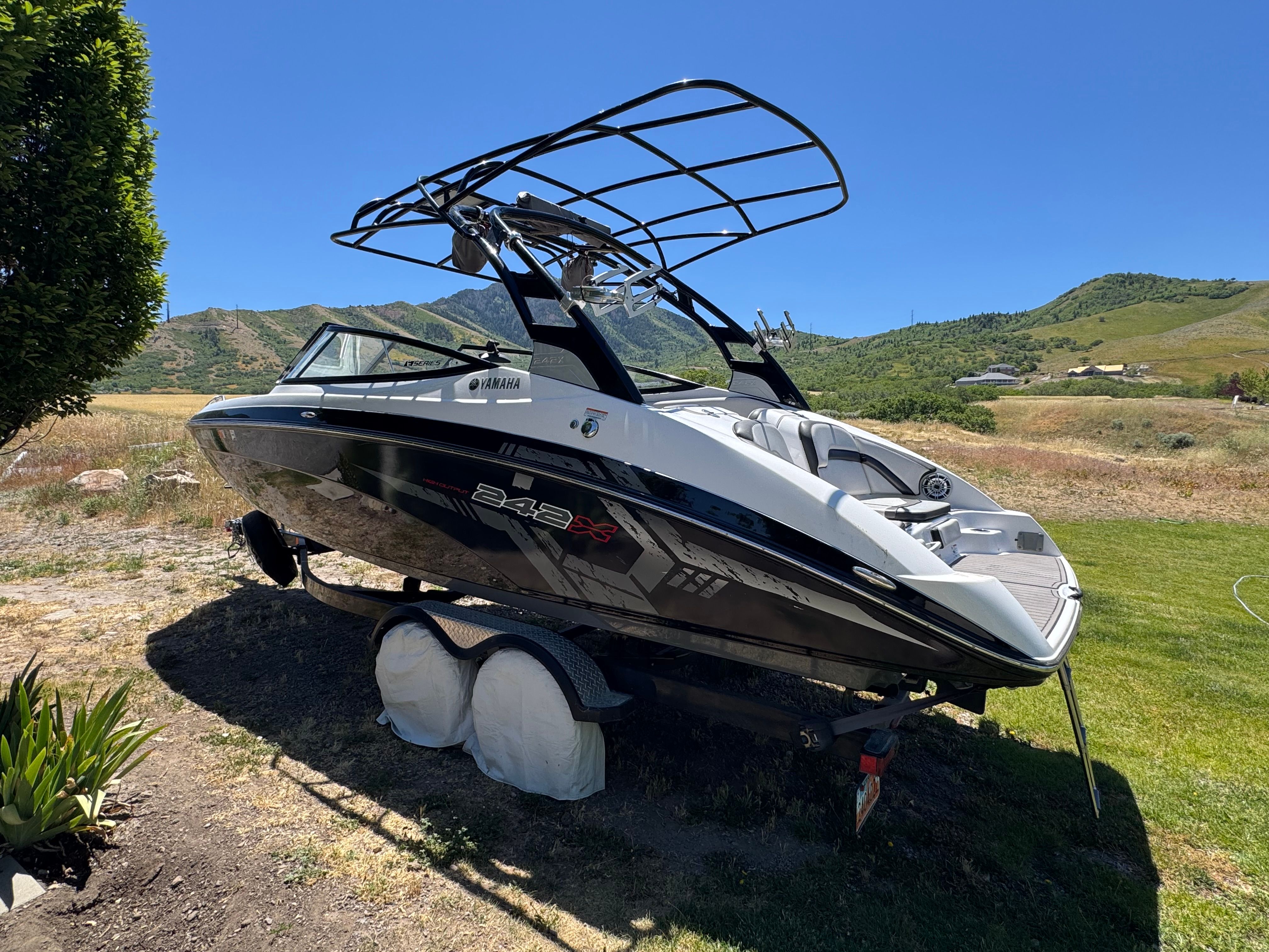 A 2017 Yamaha 242X E-Series boat on a trailer in a rural setting.