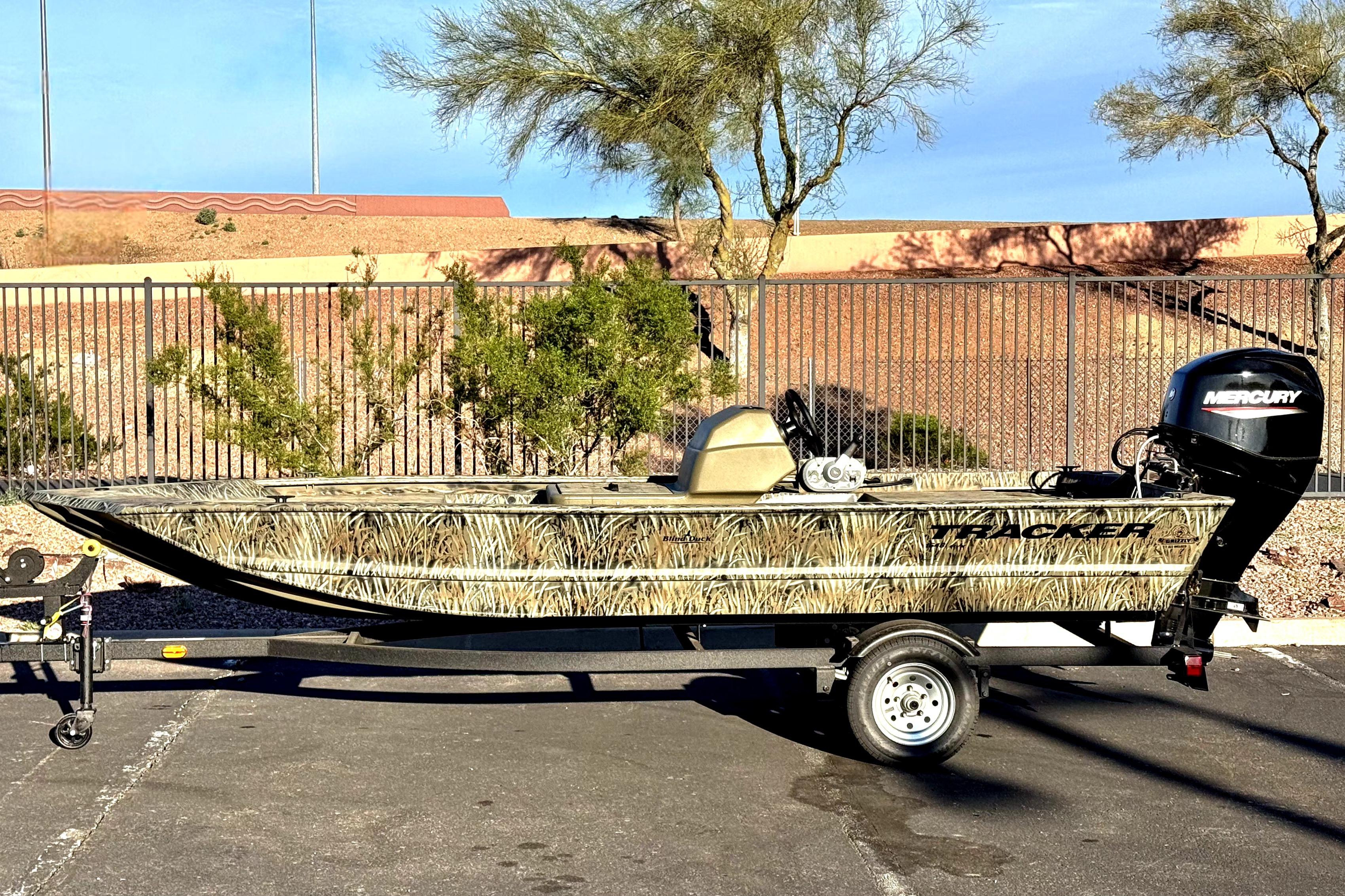 2026 Tracker Grizzly 1648 SC boat with Mercury engine on trailer, parked outdoors.
