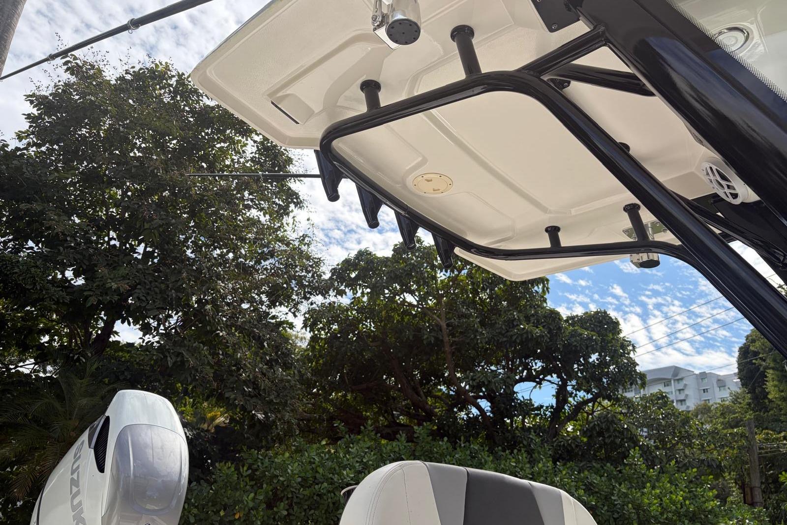 2023 Robalo 266 Cayman boat with T-top and Suzuki outboard motor, surrounded by trees.