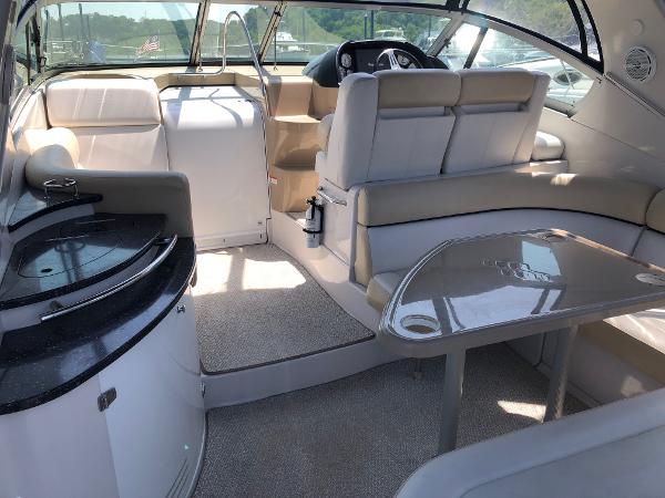 Interior of a 2008 Four Winns V338 with beige upholstery and a small table.