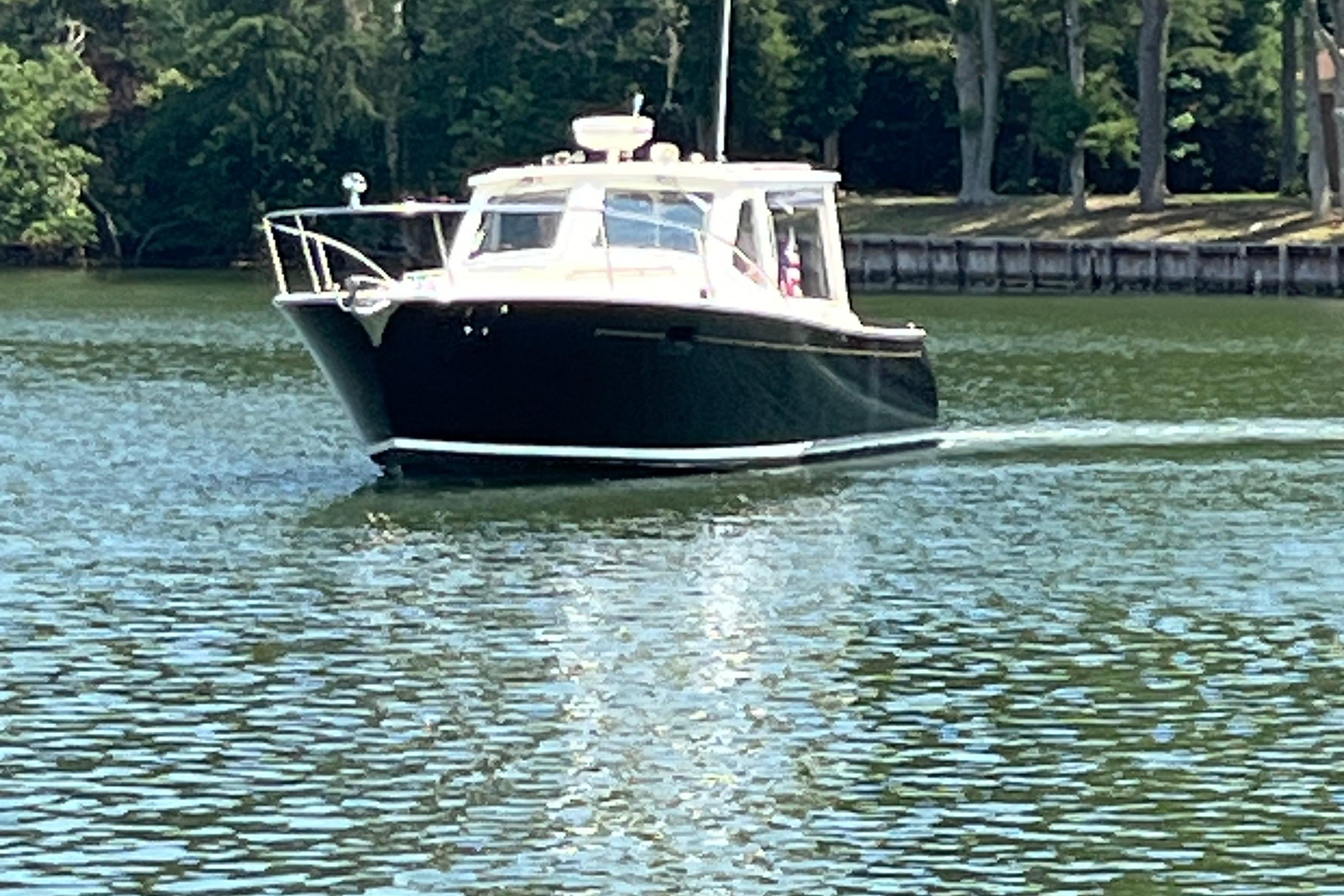 2006 MJM 34z boat cruising on a calm lake with lush green trees in the background.