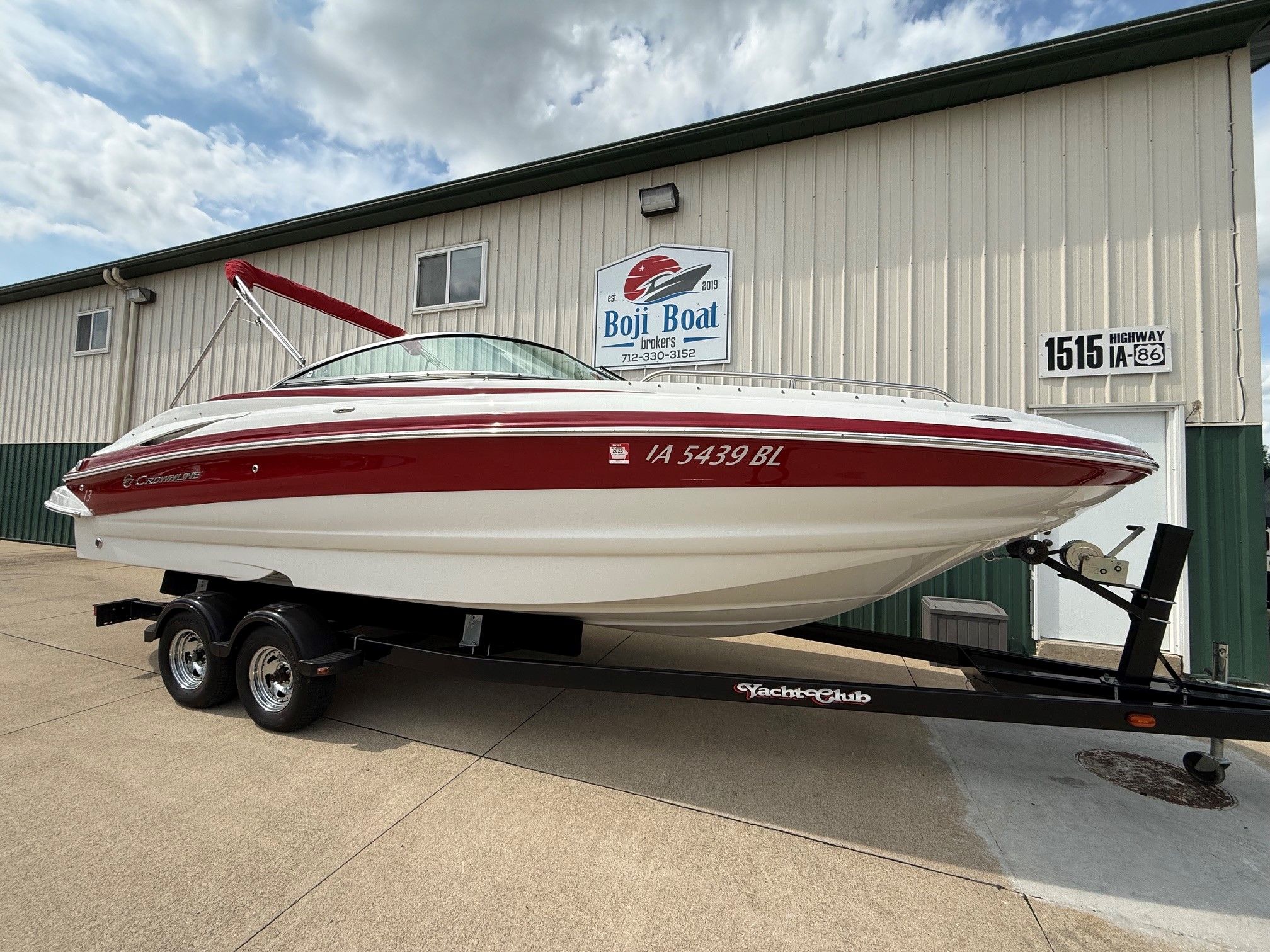 2012 Crownline 252 EX on a trailer parked in front of a building.