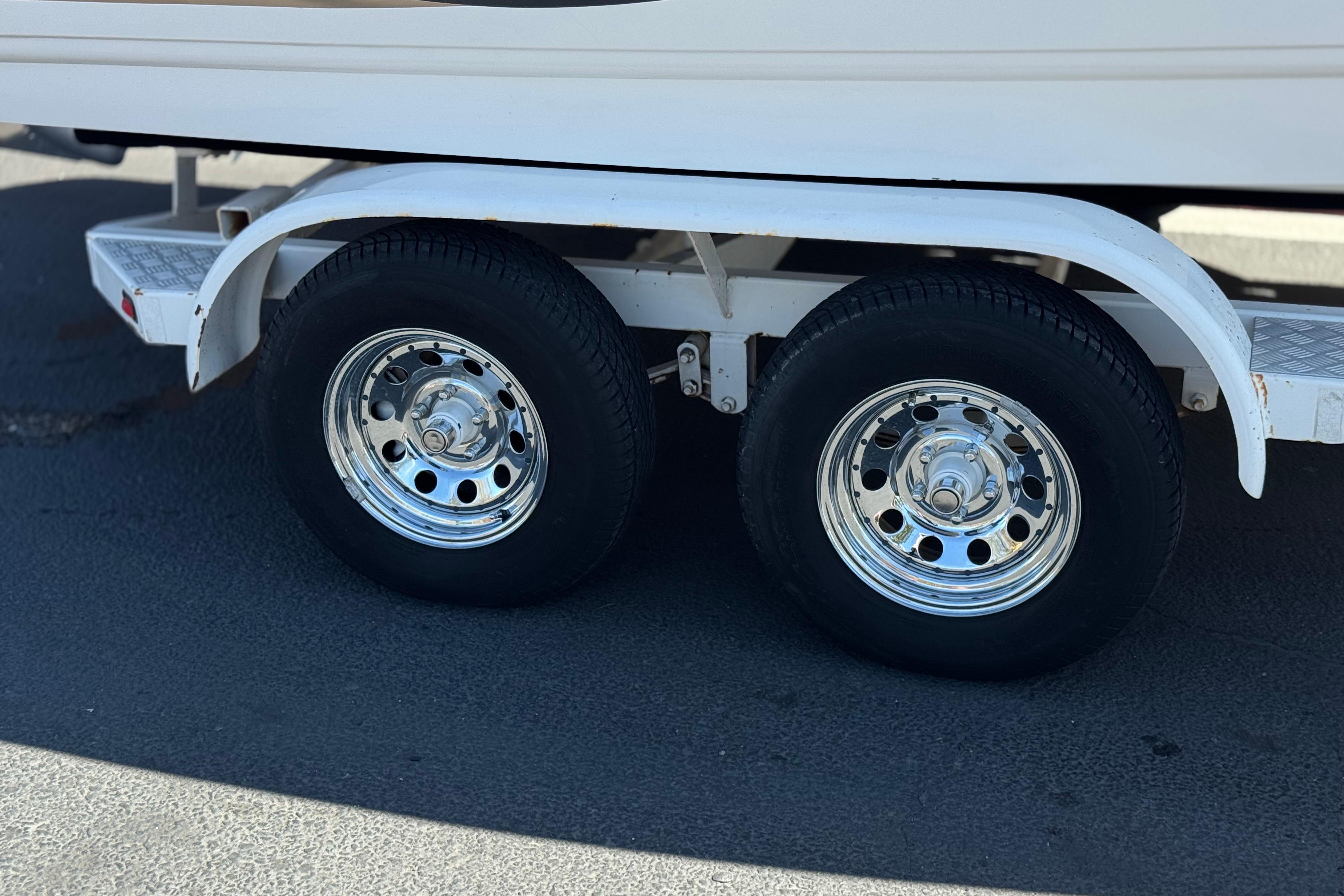 Trailer wheels of a 2002 Chaparral 186 SSi boat on pavement.