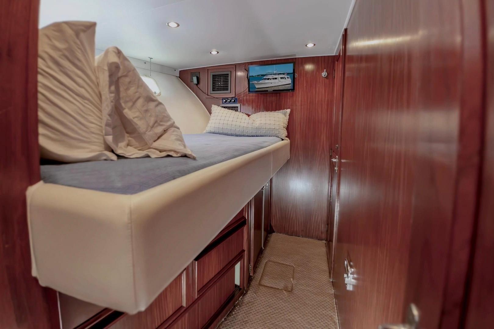 Cozy cabin interior of 1980 Hatteras 70 Motor Yacht with wooden paneling and bed.
