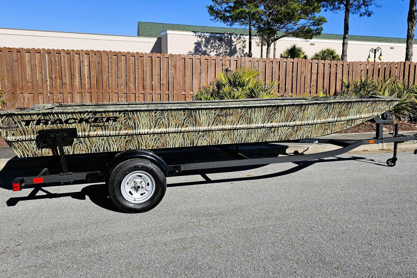 2025 Tracker Grizzly 1860 Utility boat on trailer, camo design, parked outdoors.