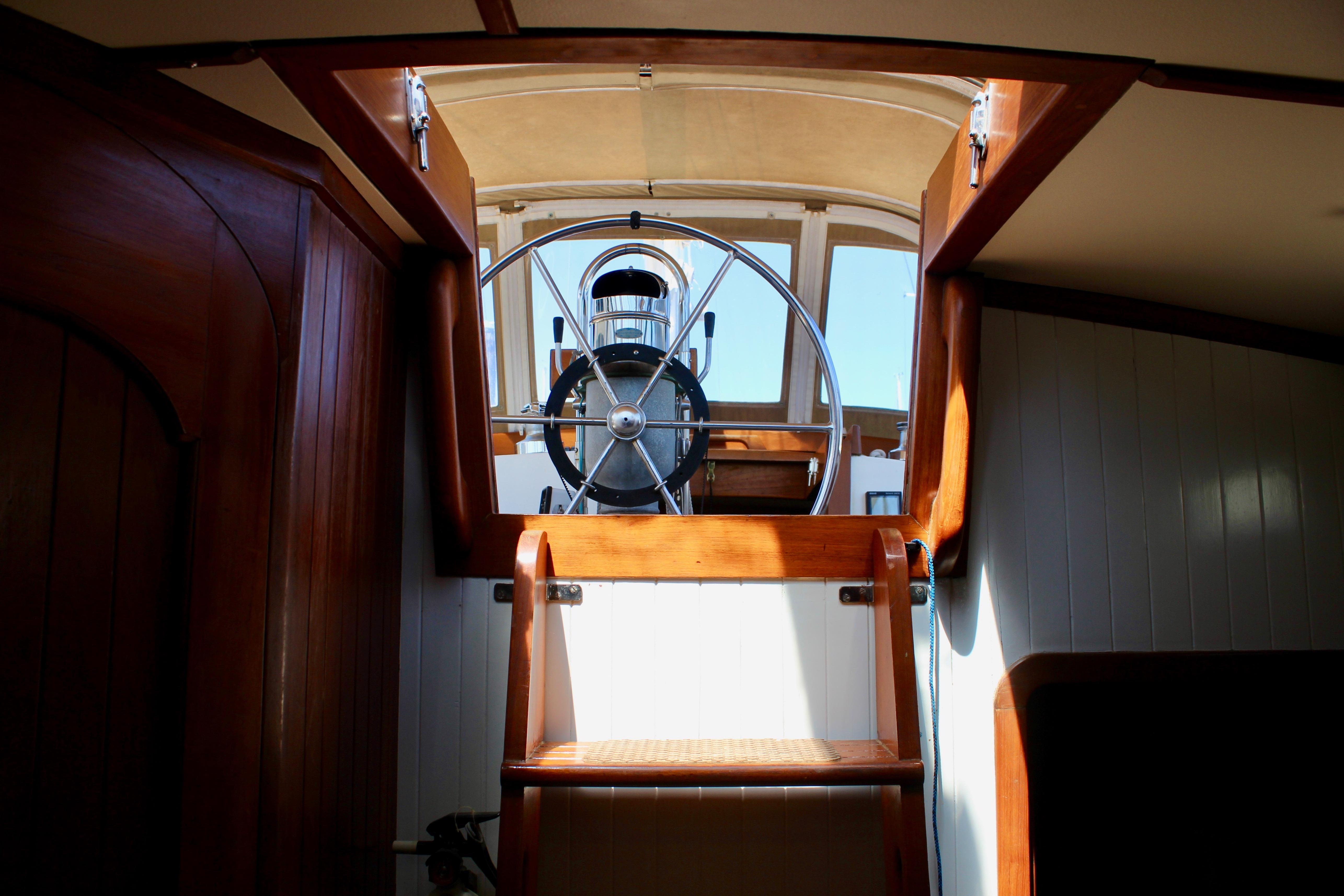 Interior view of 1981 Kelly Peterson 46 sailboat, showcasing wooden stairs and steering wheel.