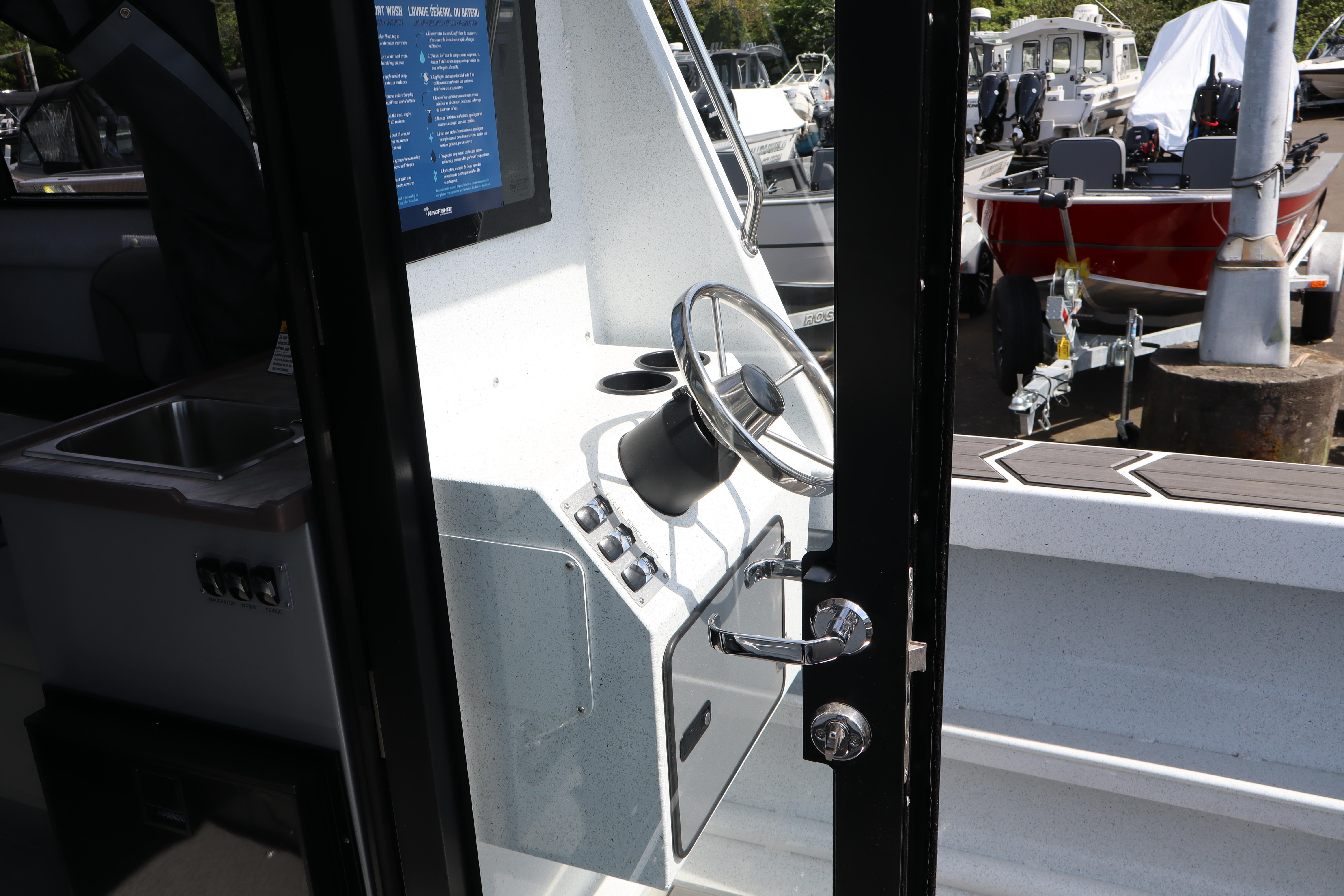 Interior view of 2026 KingFisher 25 XAC boat, showcasing steering wheel and control panel.