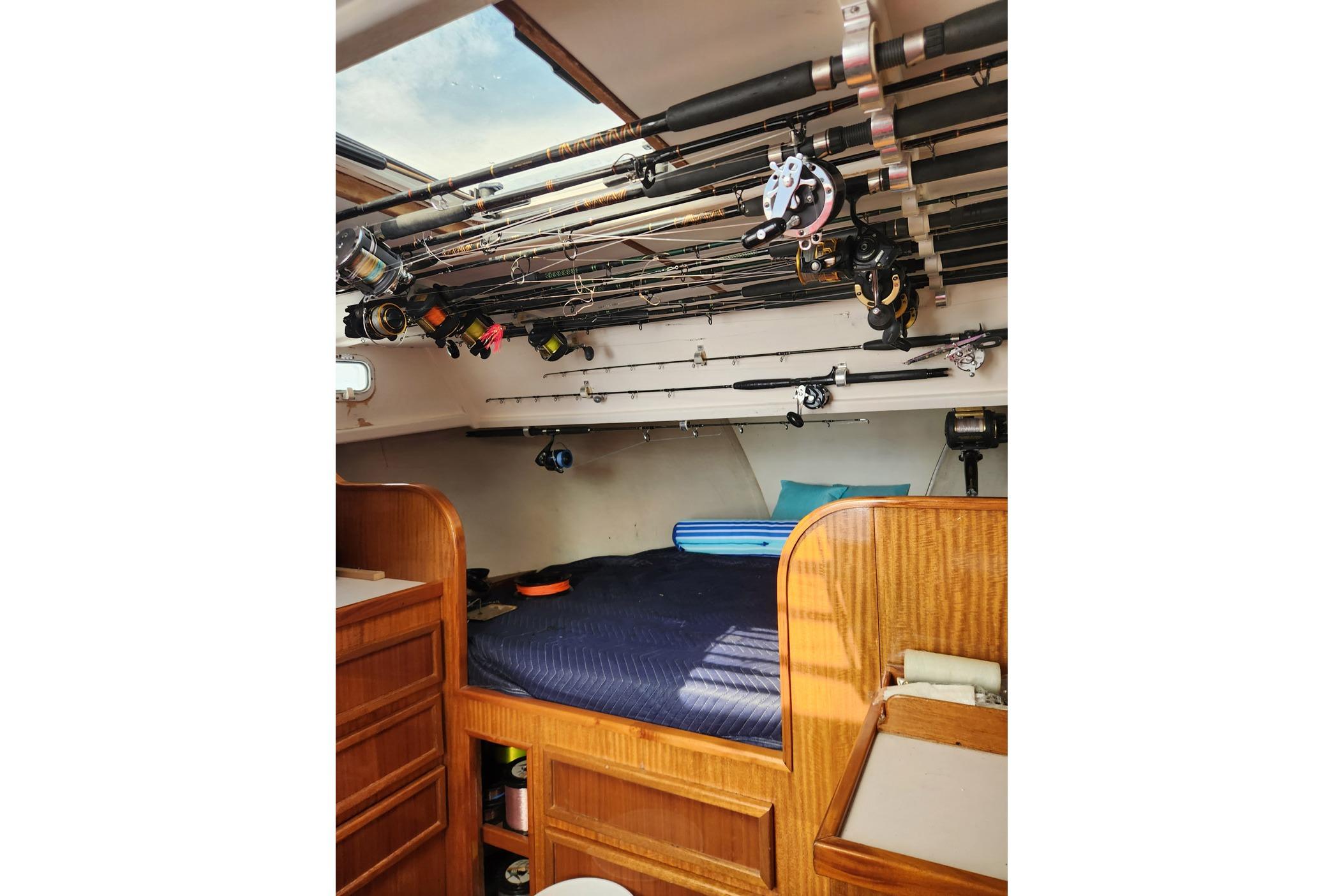 Interior of 1987 Young Brothers Custom Sport Fish boat with fishing rods and cozy bed.