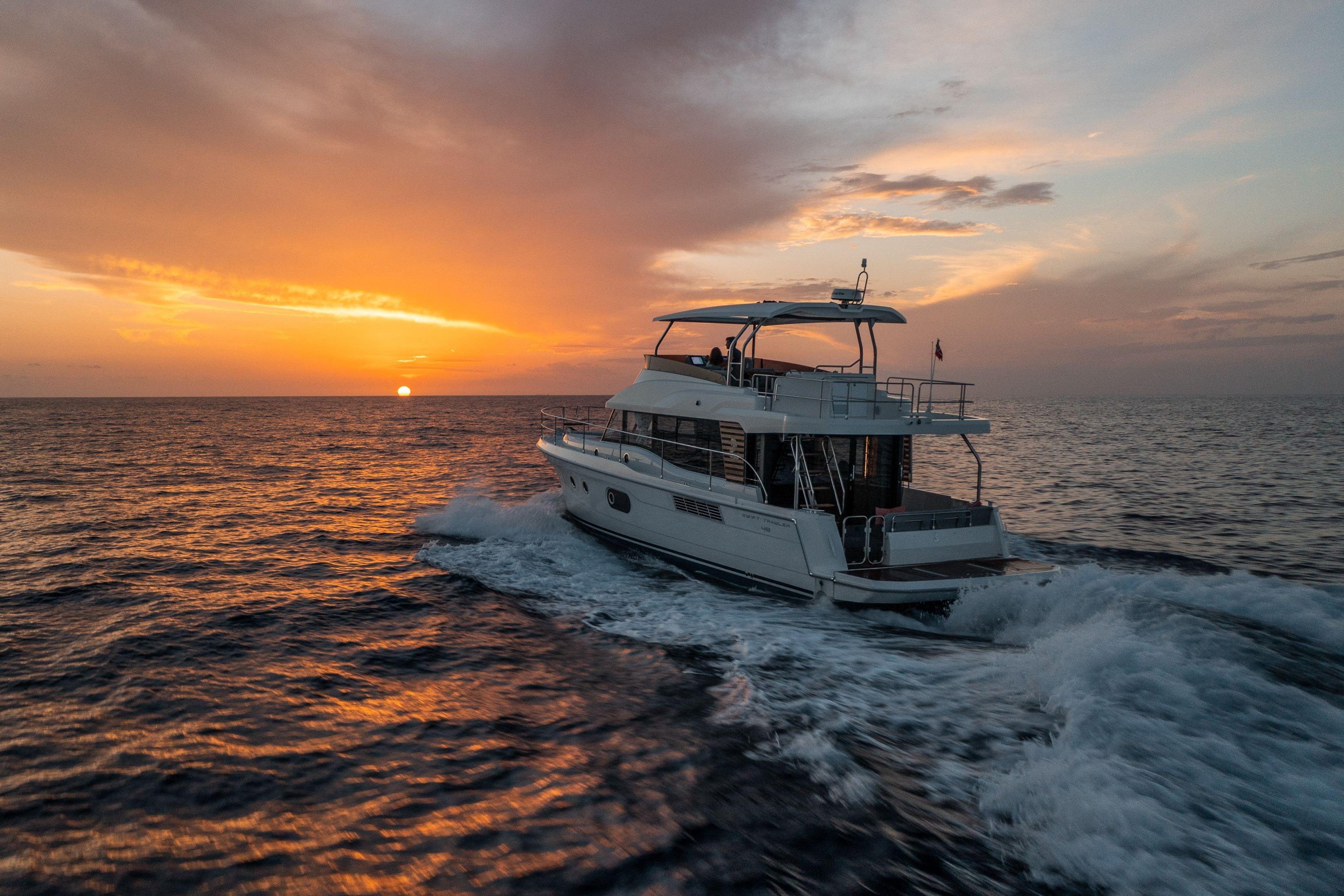 2026 Beneteau Swift Trawler 48 cruising at sunset on open sea.