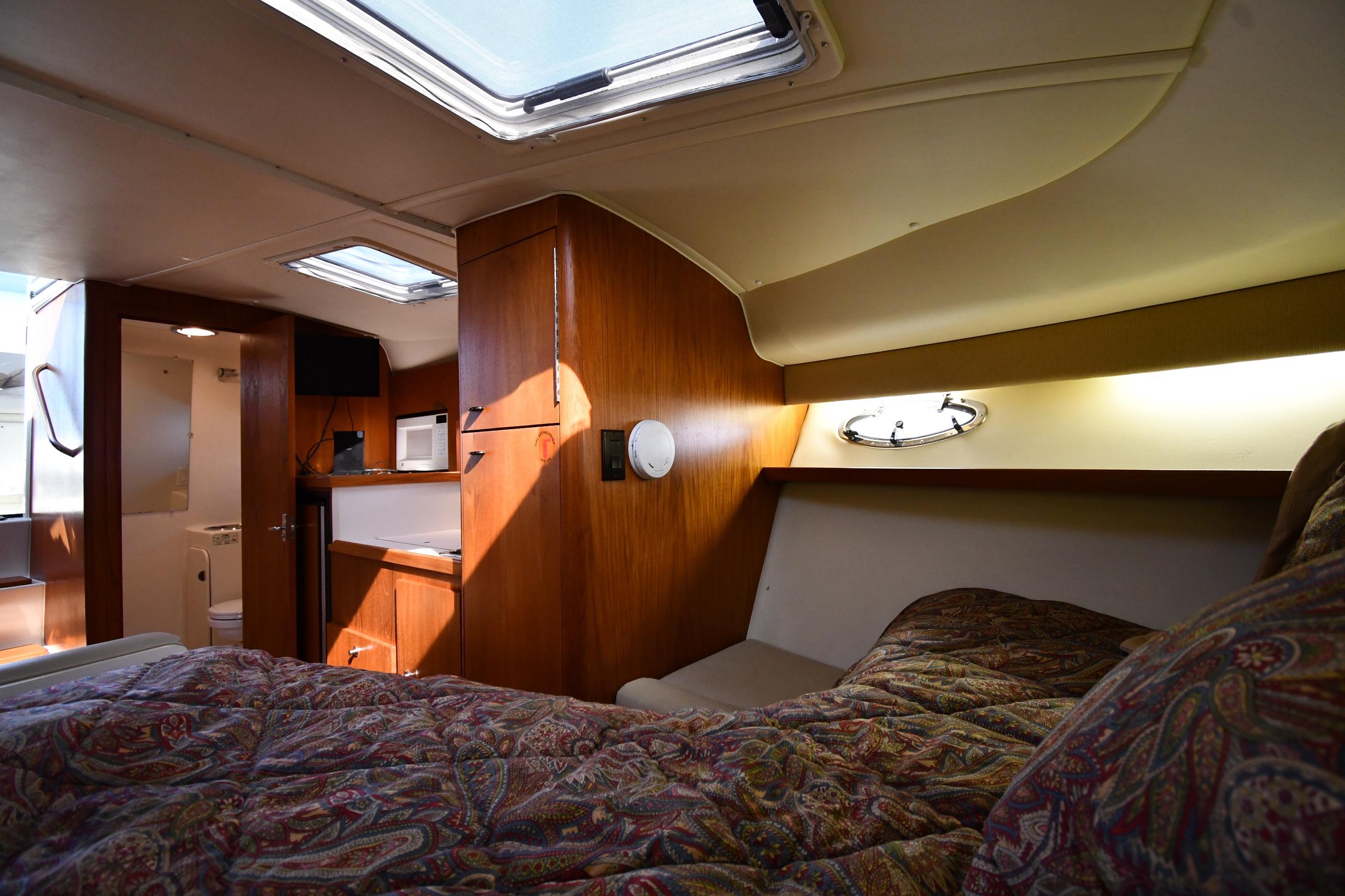 Cozy cabin interior of 1998 Tiara Yachts 3100 Open with wood finish and bedding.