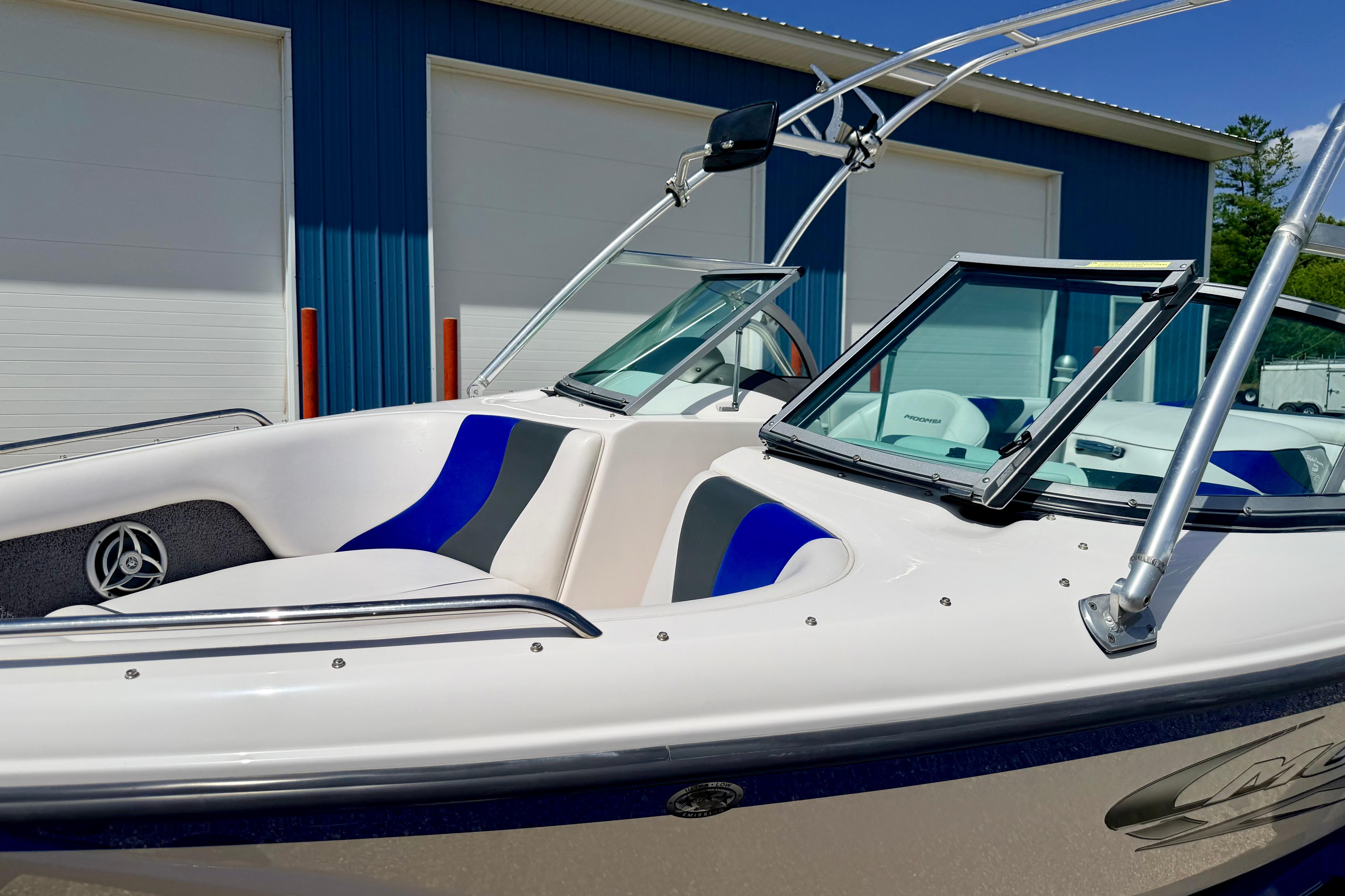 2008 Moomba Outback V boat with blue and white interior, parked near blue building.