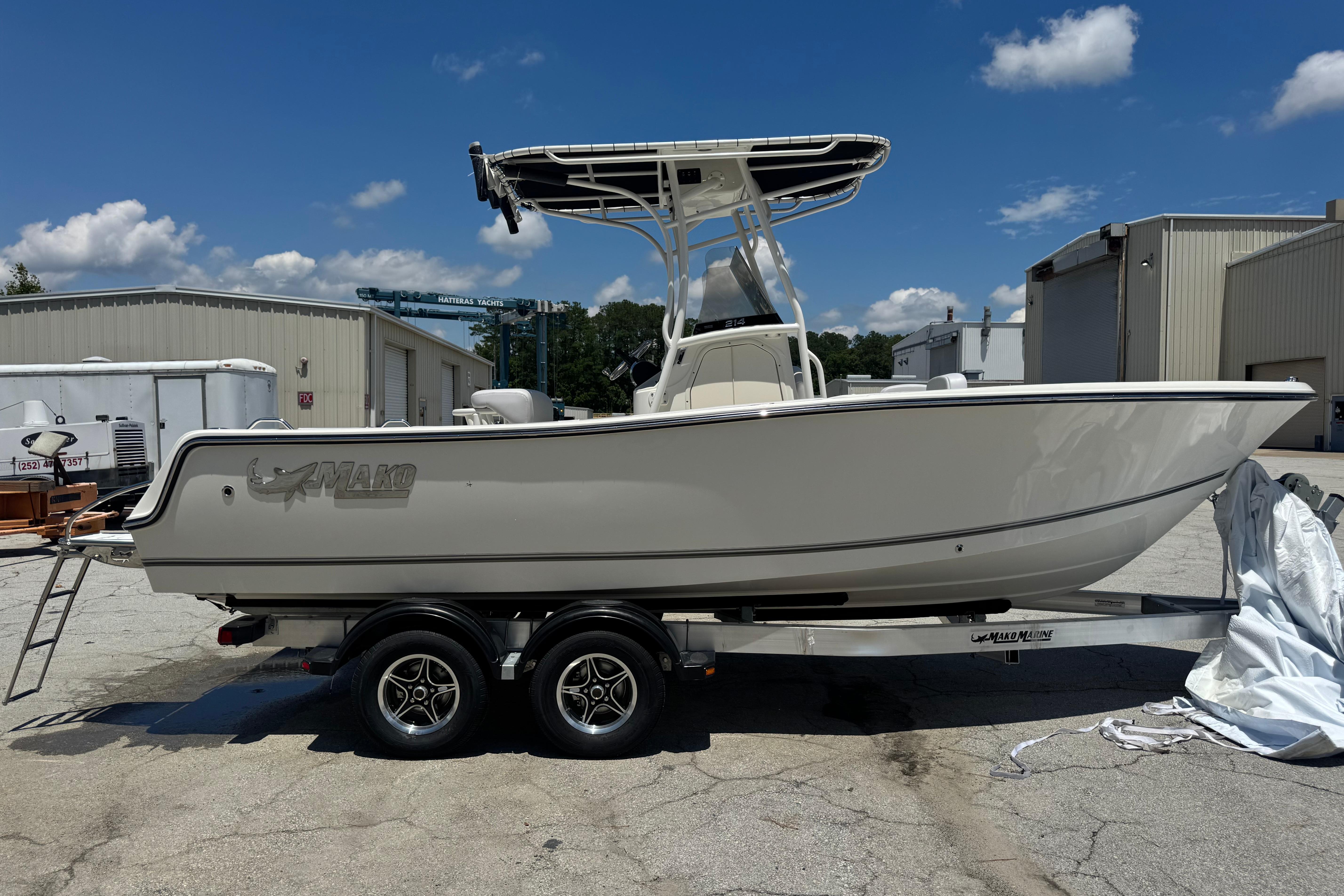 2026 Mako 214 Center Console boat on trailer, parked outdoors under blue sky.