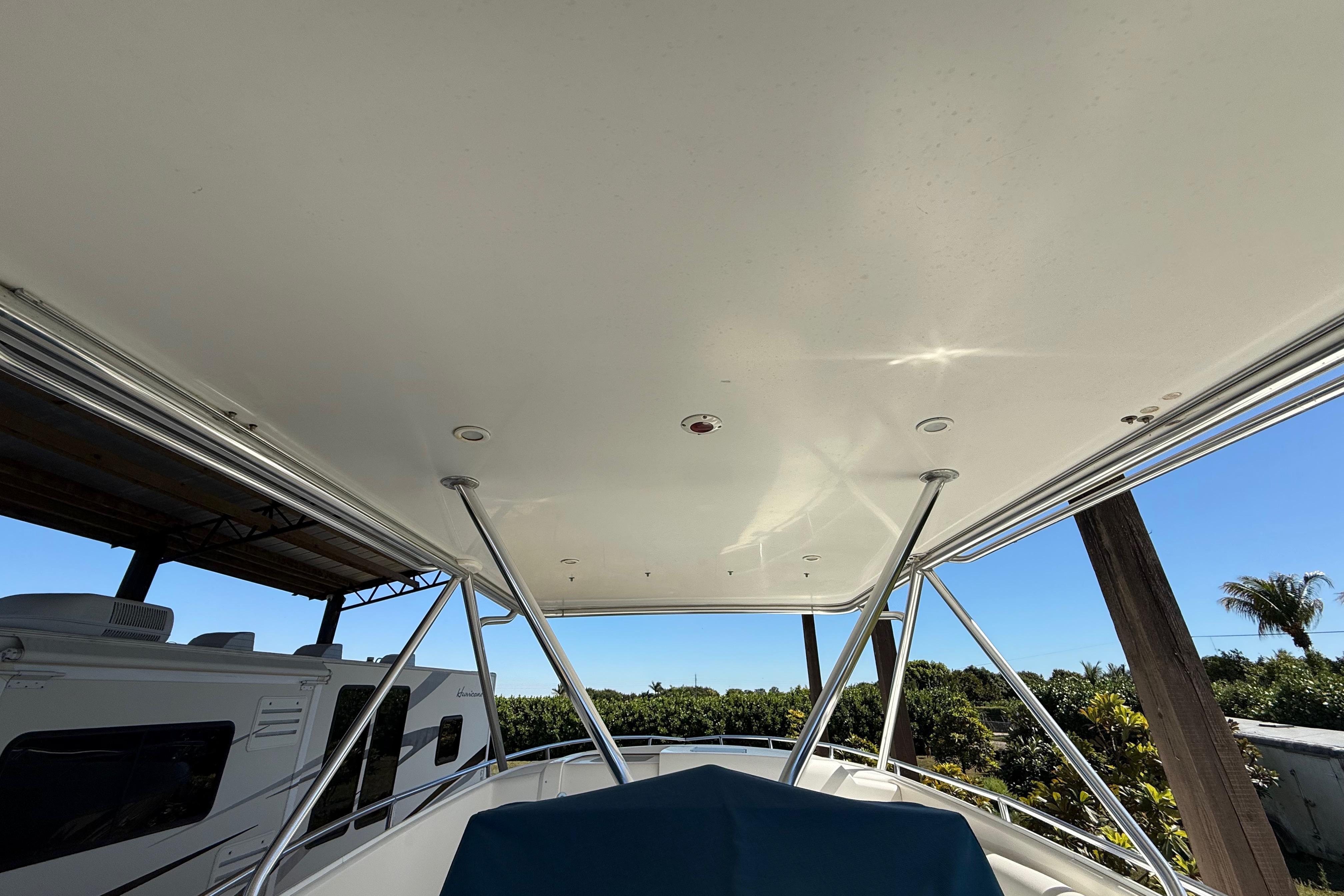 2008 Intrepid 377 Walkaround boat canopy with support poles, surrounded by greenery.
