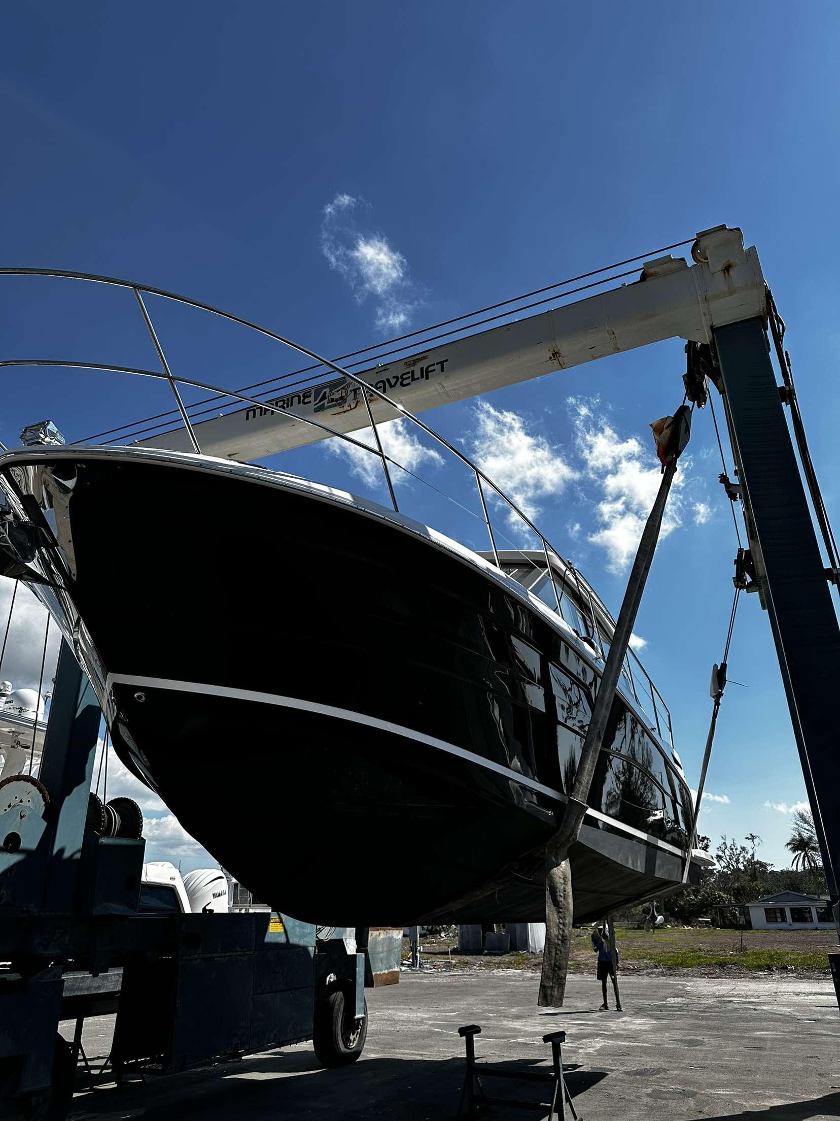 2021 Regal 38 XO yacht being lifted by a crane under a clear blue sky.
