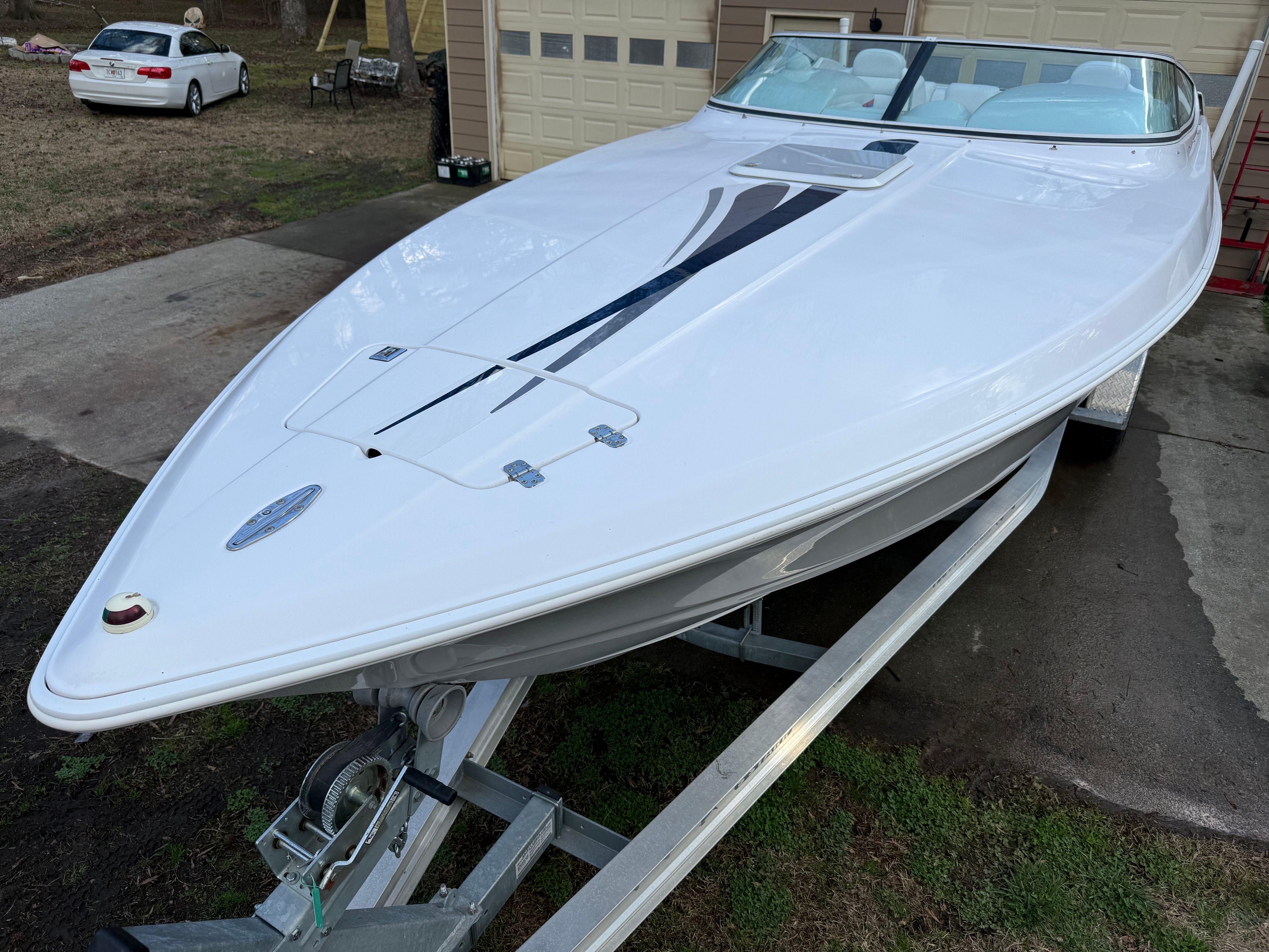 A white 2003 Donzi 28 ZX boat on a trailer in front of a garage.