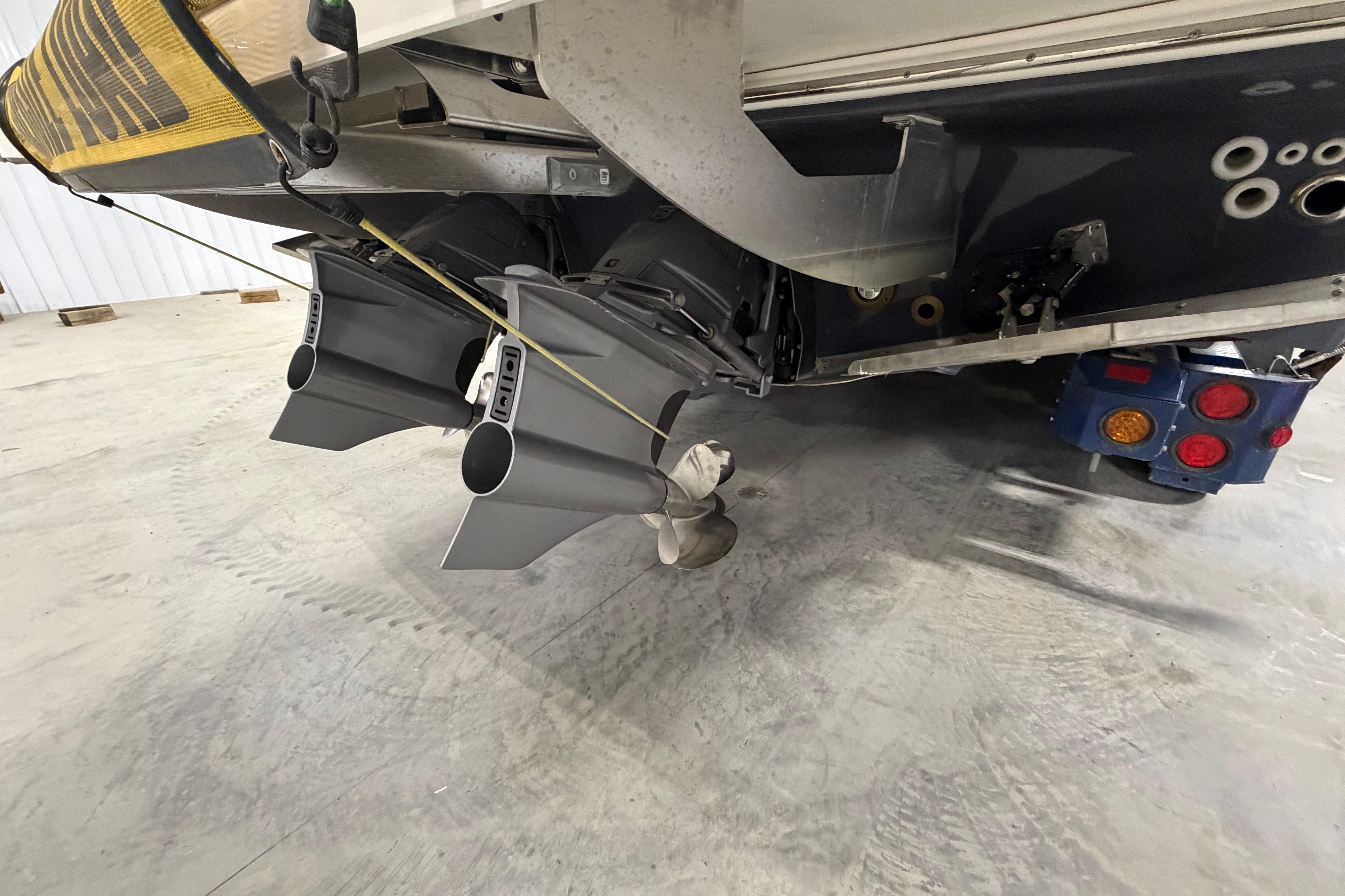 2027 Regal 38 Surf boat's stern with dual propellers in a garage setting.