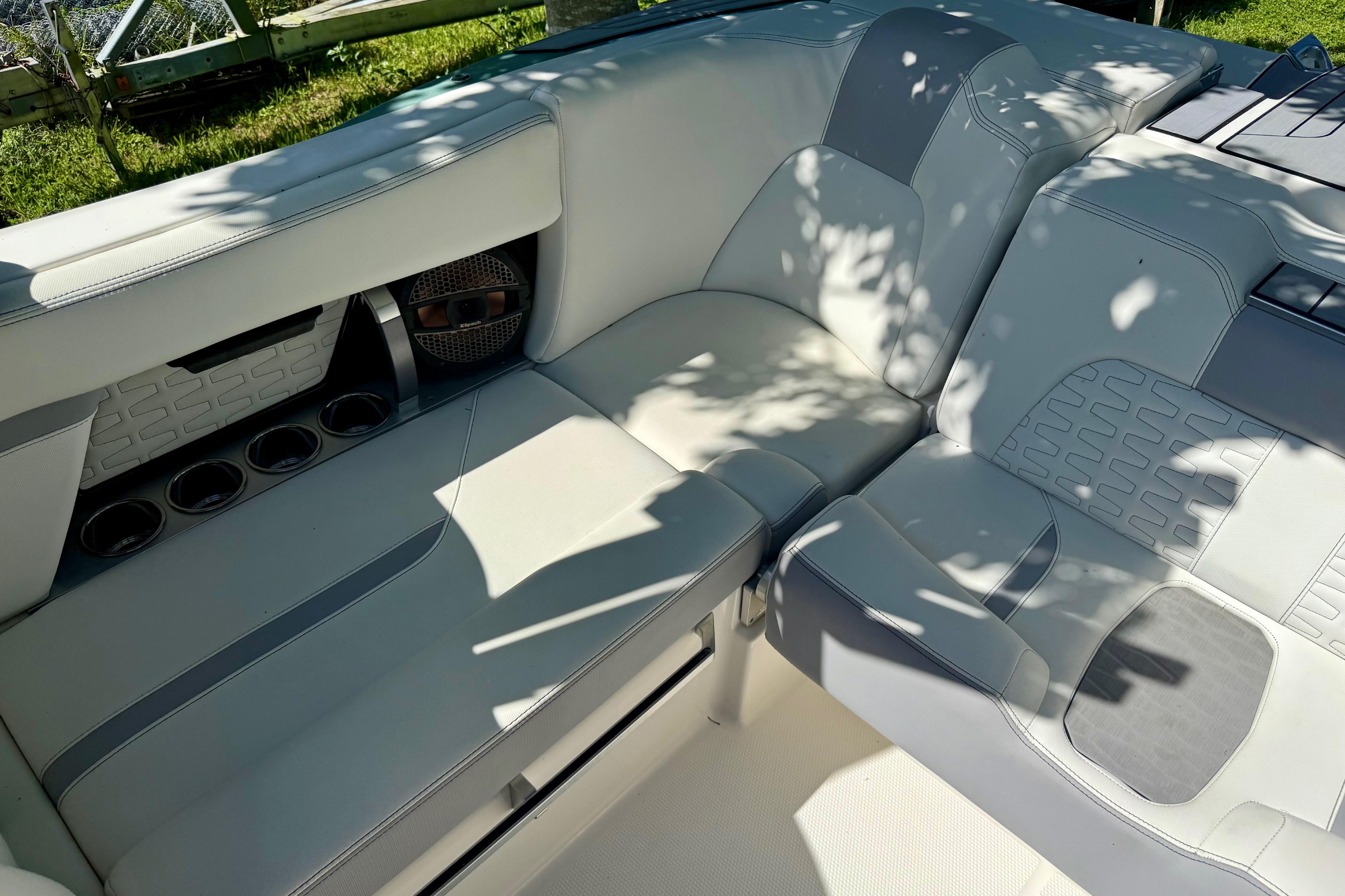 2023 MasterCraft X24 boat interior with white and gray seating, cup holders, and speaker.