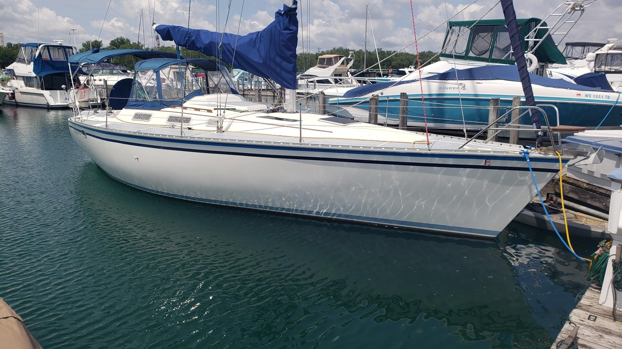 1989 Hunter Legend 37 sailboat docked in a marina, featuring blue accents and a covered cockpit.