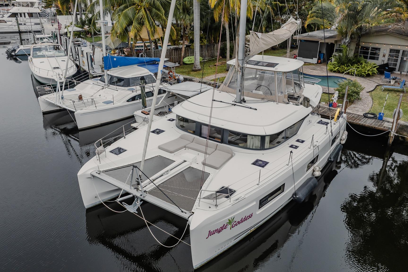 2022 Lagoon 46 catamaran docked in a marina, surrounded by palm trees.