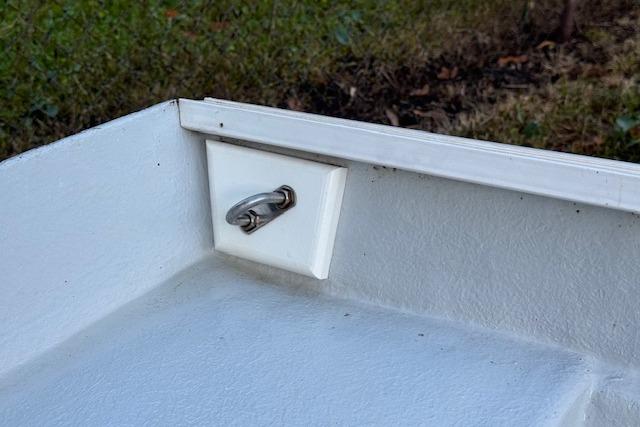 1999 Beacon Boats Pram corner detail with metal cleat, white interior, and grassy background.