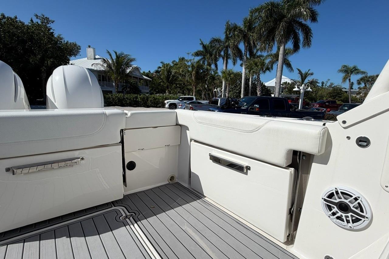 2021 Pursuit DC 266 Dual Console boat interior with seating and speaker, surrounded by palm trees.