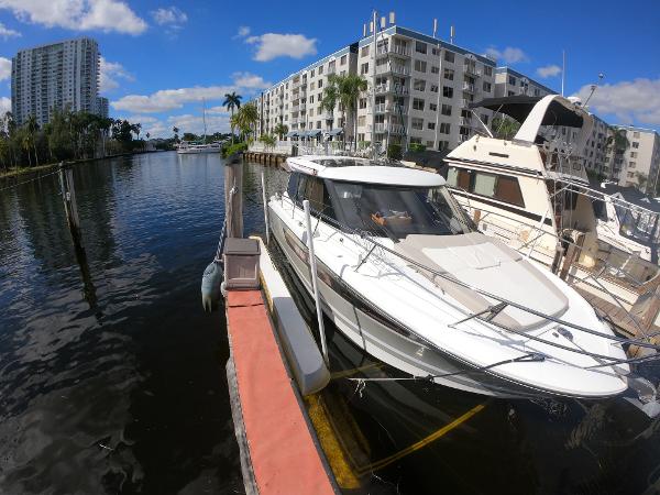 2017 Jeanneau NC 11 docked in a marina with waterfront apartments.
