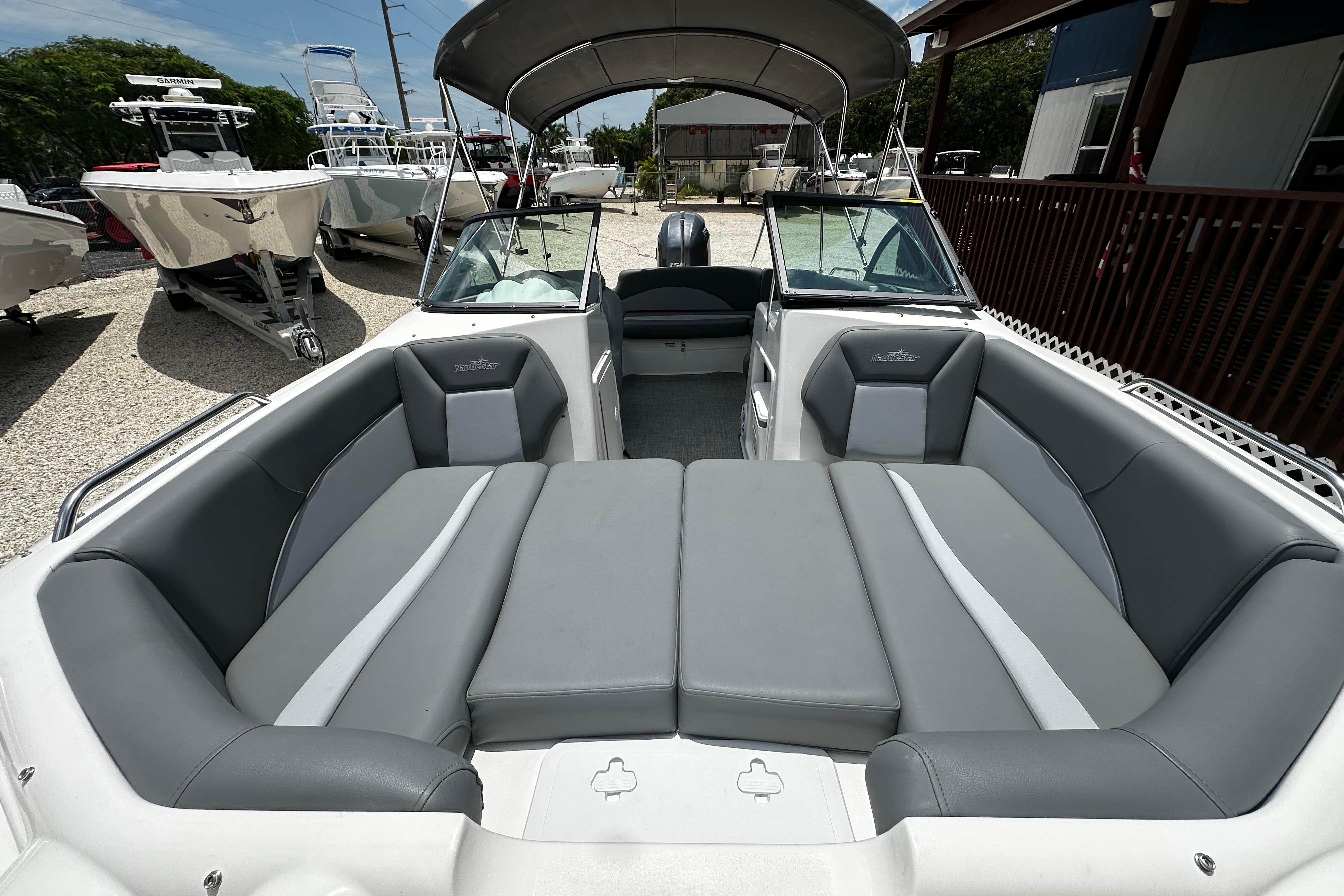2024 NauticStar 203 DC Deck boat with spacious seating and canopy in a marina.