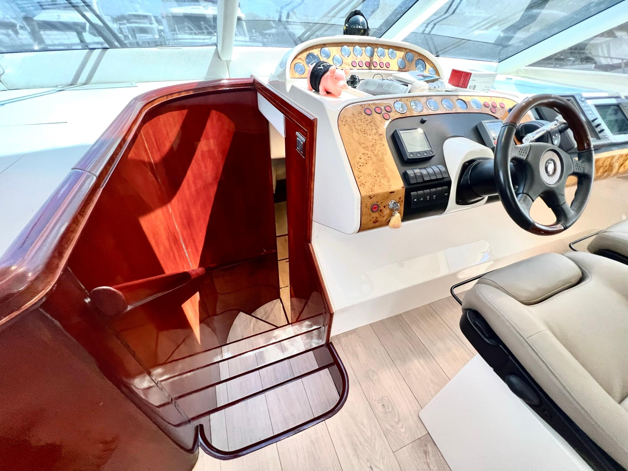 1999 Fairline Squadron 65 yacht helm station with wooden stairs and modern controls.