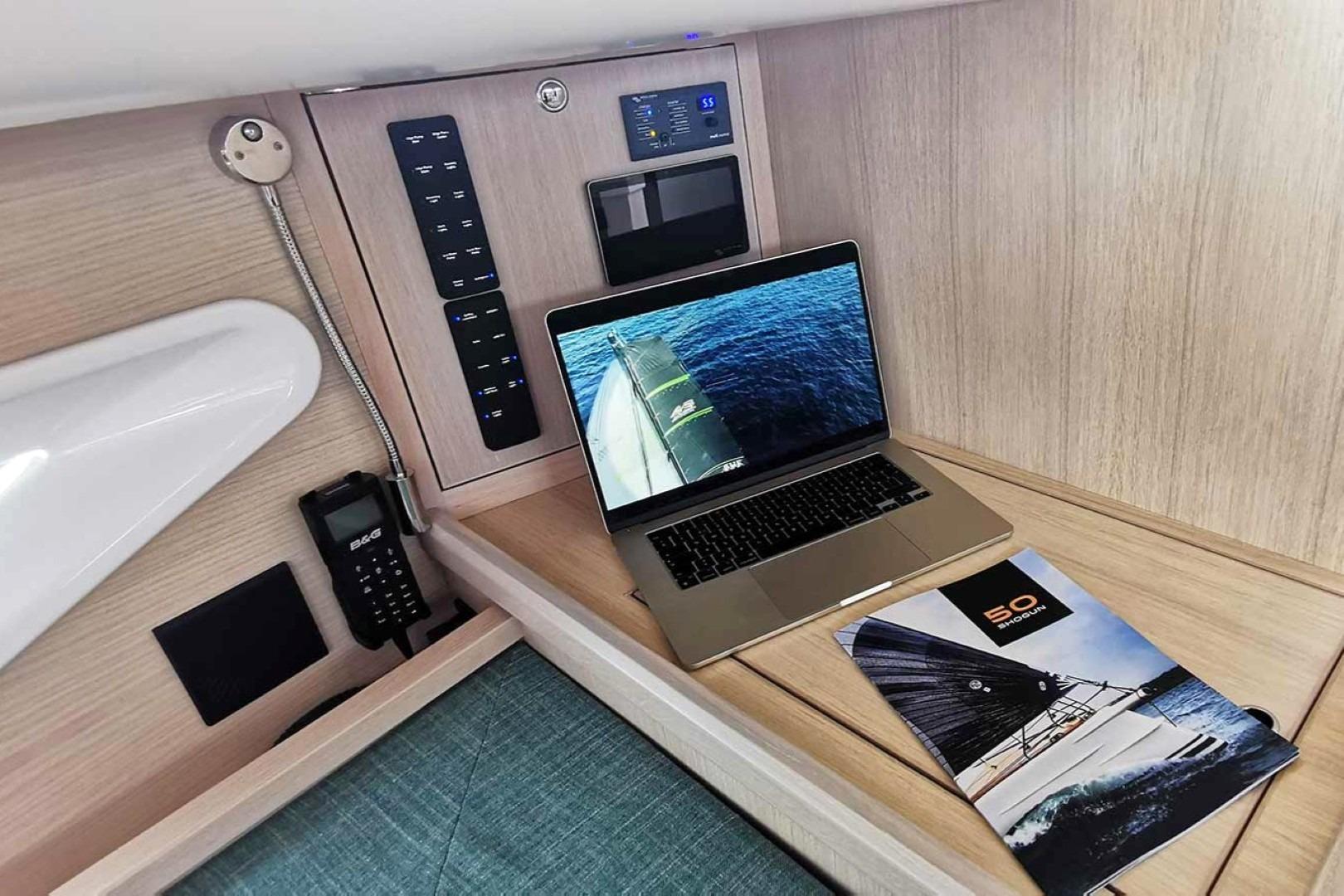 Modern yacht interior with laptop, control panel, and Shogun 43 brochure, 2025 model.