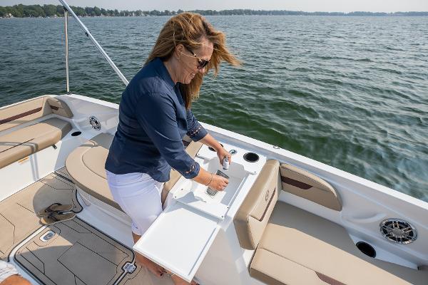 Woman enjoying 2025 Hurricane SunDeck Sport 205 OB boat on a sunny day.