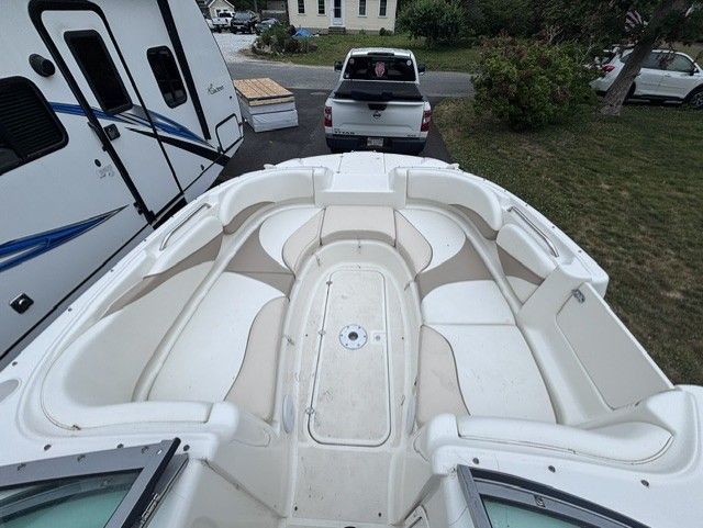 2003 Glastron DX 235 with spacious, cushioned bow area, parked next to an RV.
