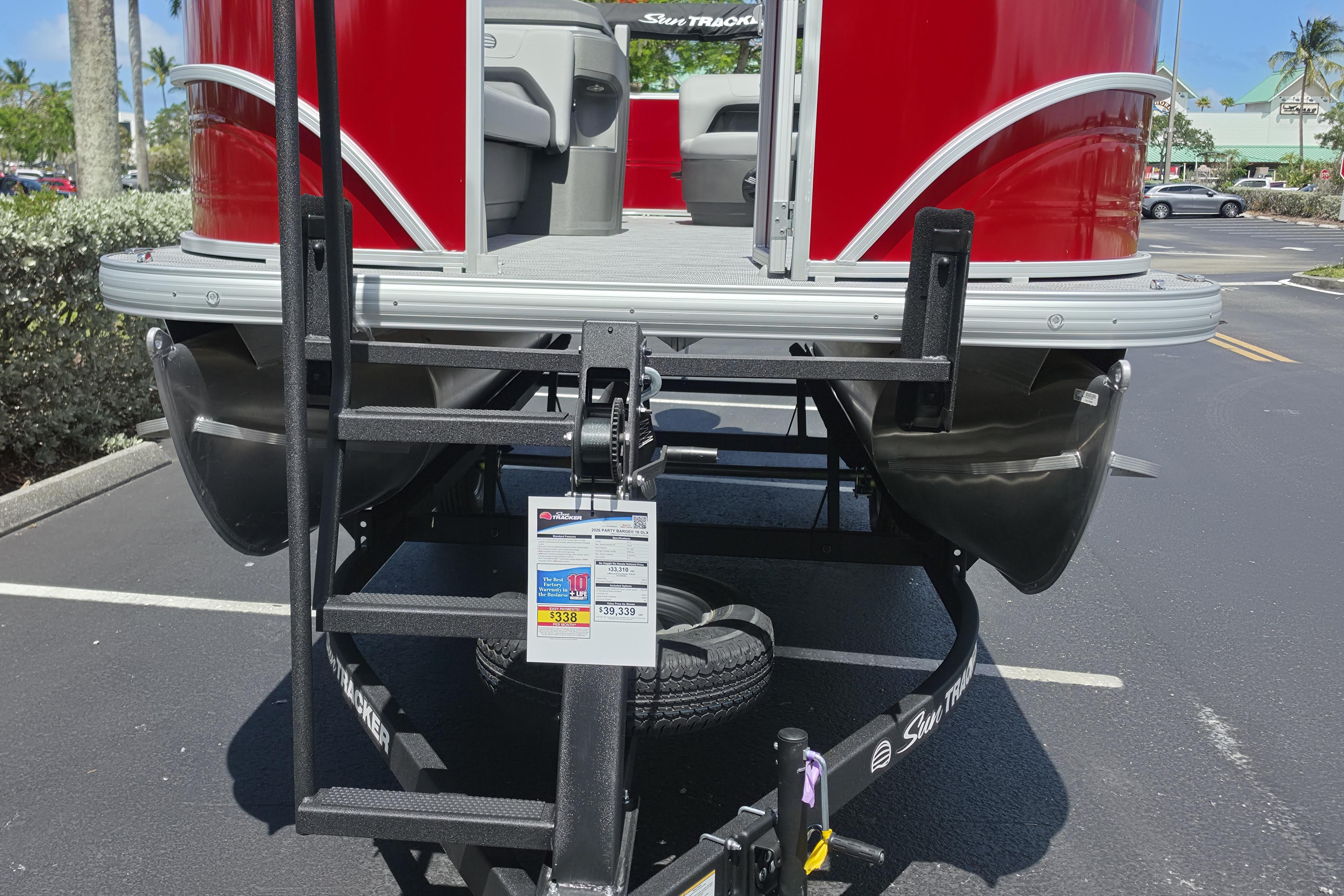 2026 Sun Tracker Party Barge 18 DLX pontoon boat on trailer in parking lot.