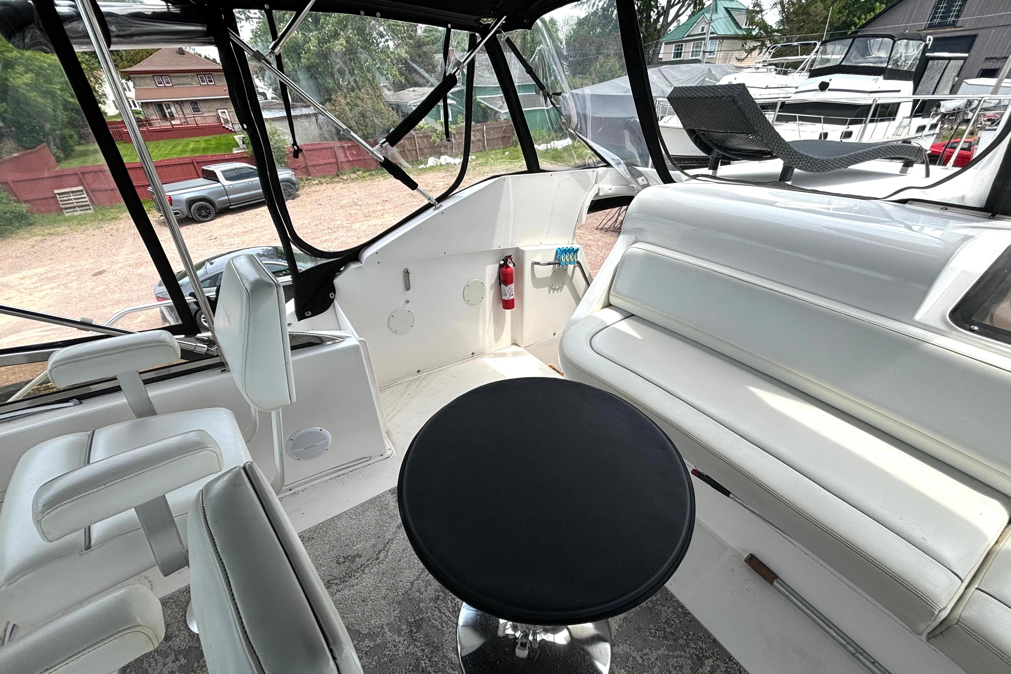 Interior view of a 1999 Silverton 453 Motor Yacht with white seating and a black table.
