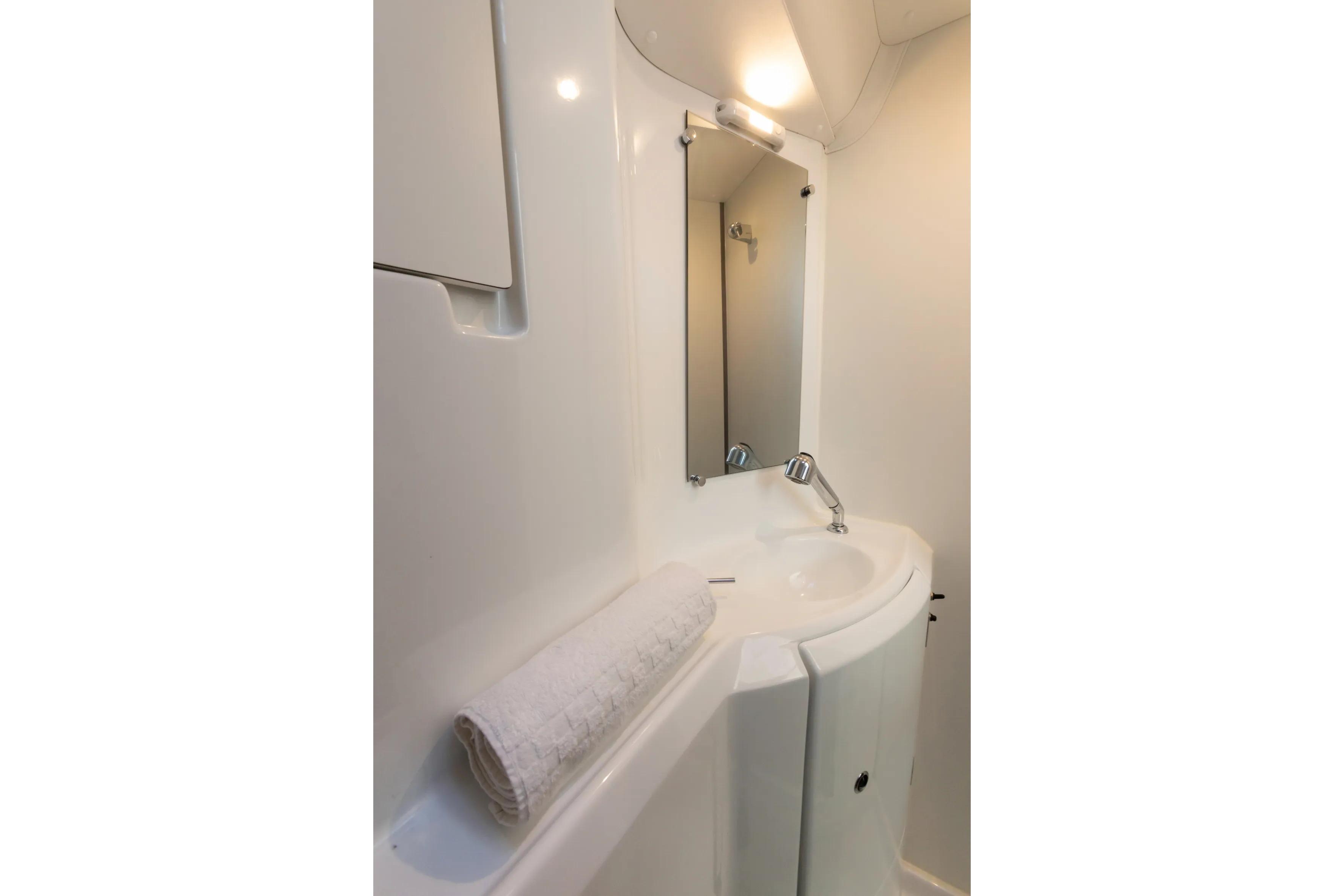 Compact bathroom in 2019 Lagoon 380 yacht with sink, mirror, and towel.