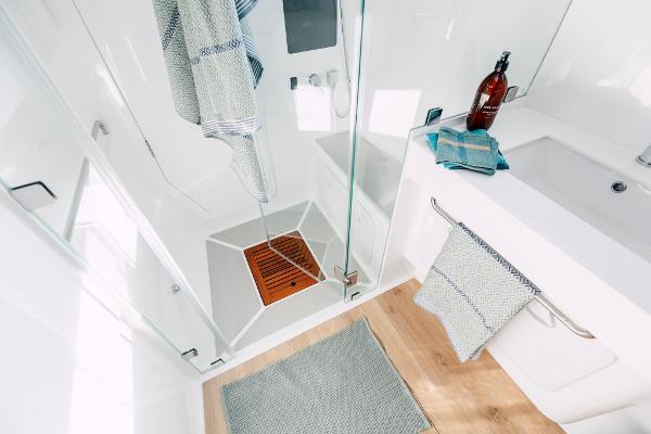 Modern bathroom with glass shower, wooden floor, and stylish towels; Vision 444, 2026 model.