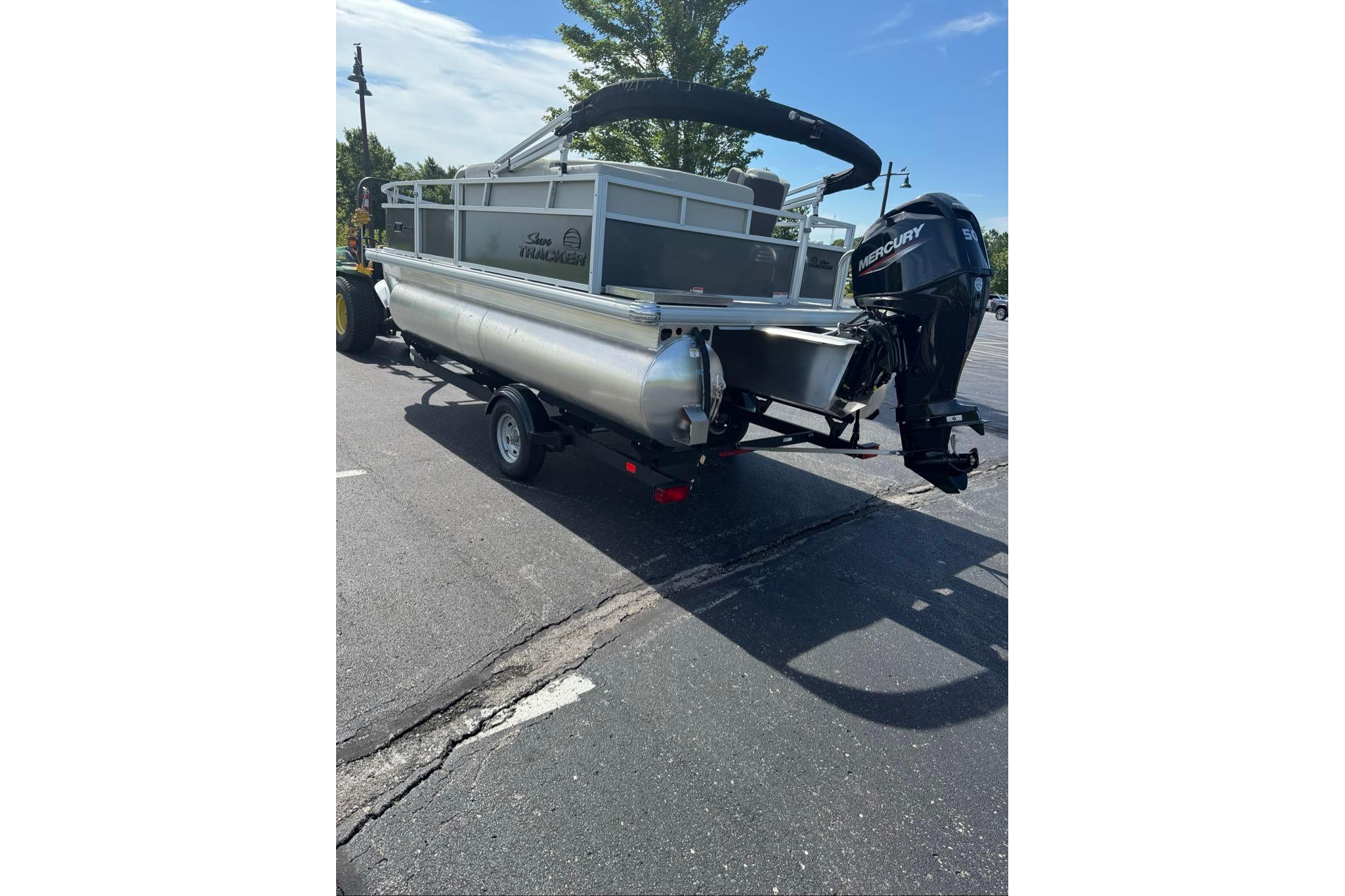 2026 Sun Tracker Bass Buggy 16 XL Select pontoon boat with Mercury outboard motor in parking lot.
