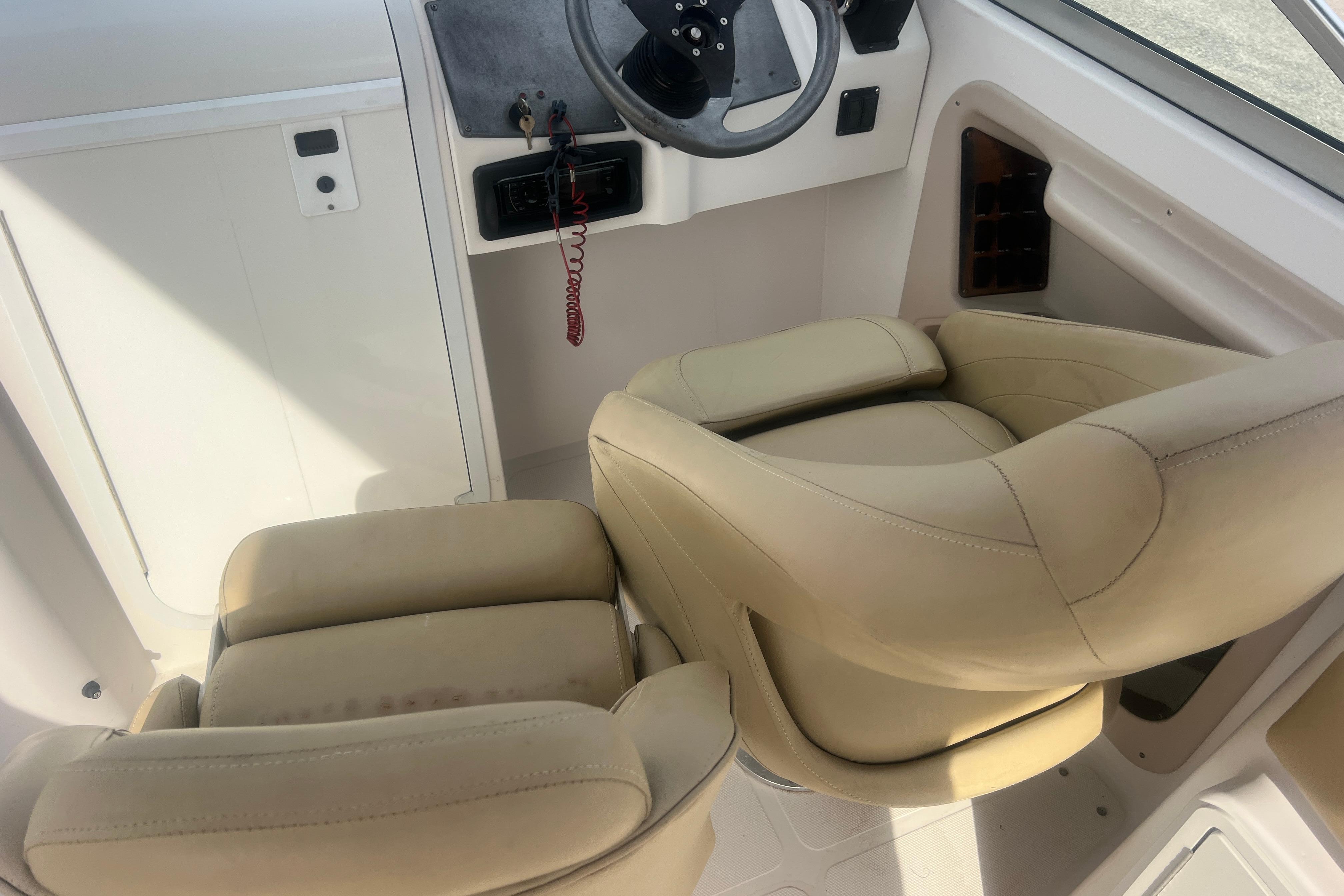 2002 Hurricane SunDeck 260 OB boat interior with beige captain's chairs and steering console.