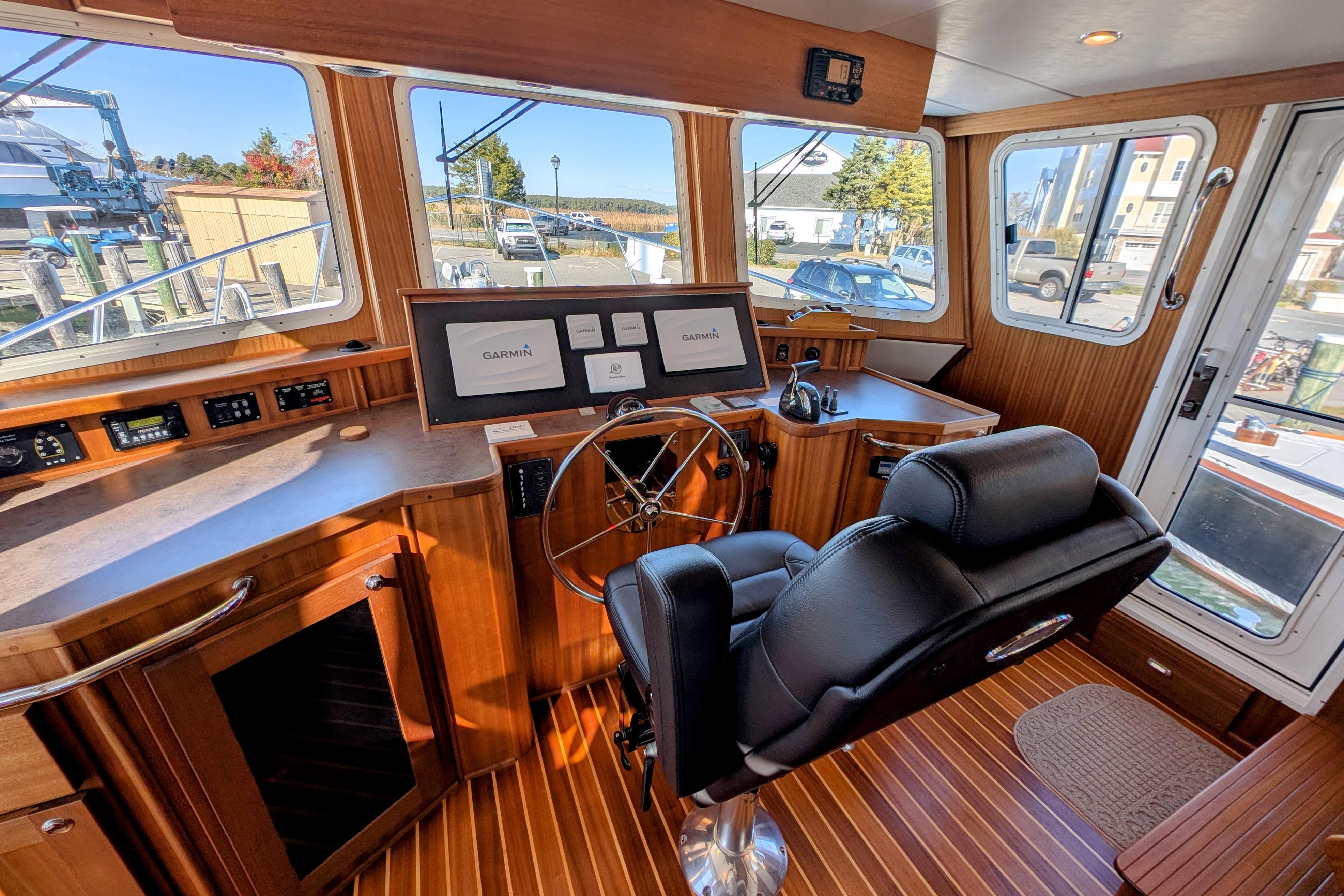 Pilothouse of 2015 American Tug 435 with Garmin navigation, wood paneling, and captain's chair.