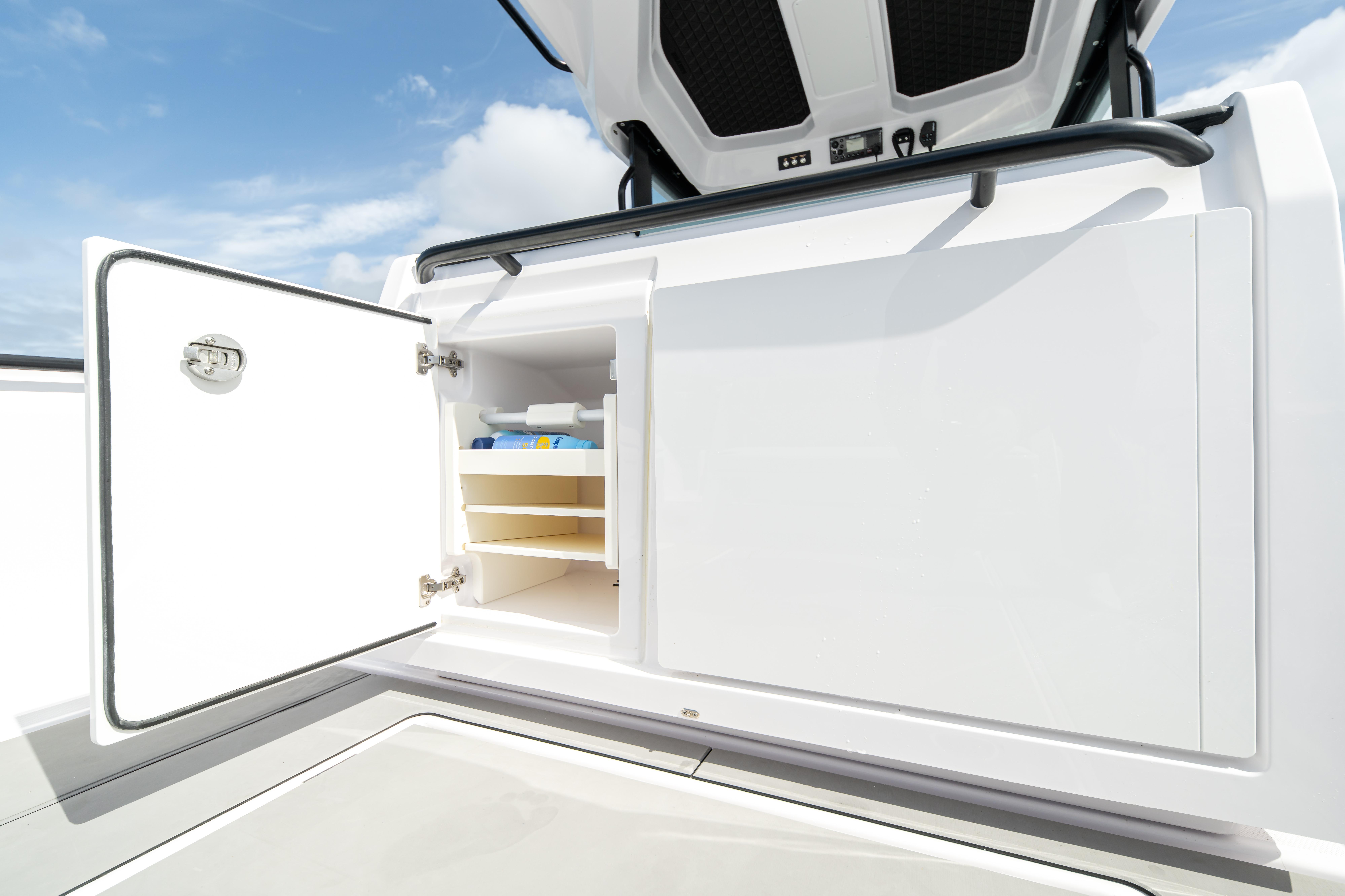 2025 Axopar 29 CCX boat storage compartment with open door under a clear sky.