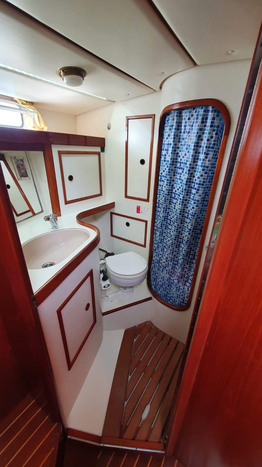 1992 Contest 43 yacht bathroom with wooden accents and blue mosaic shower curtain.