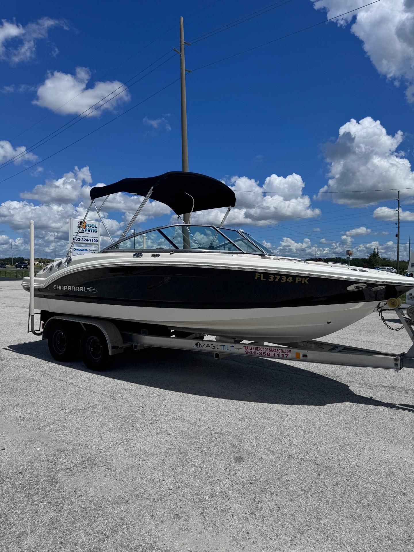 A 2013 Chaparral 206 SSi boat on a trailer under a blue sky.