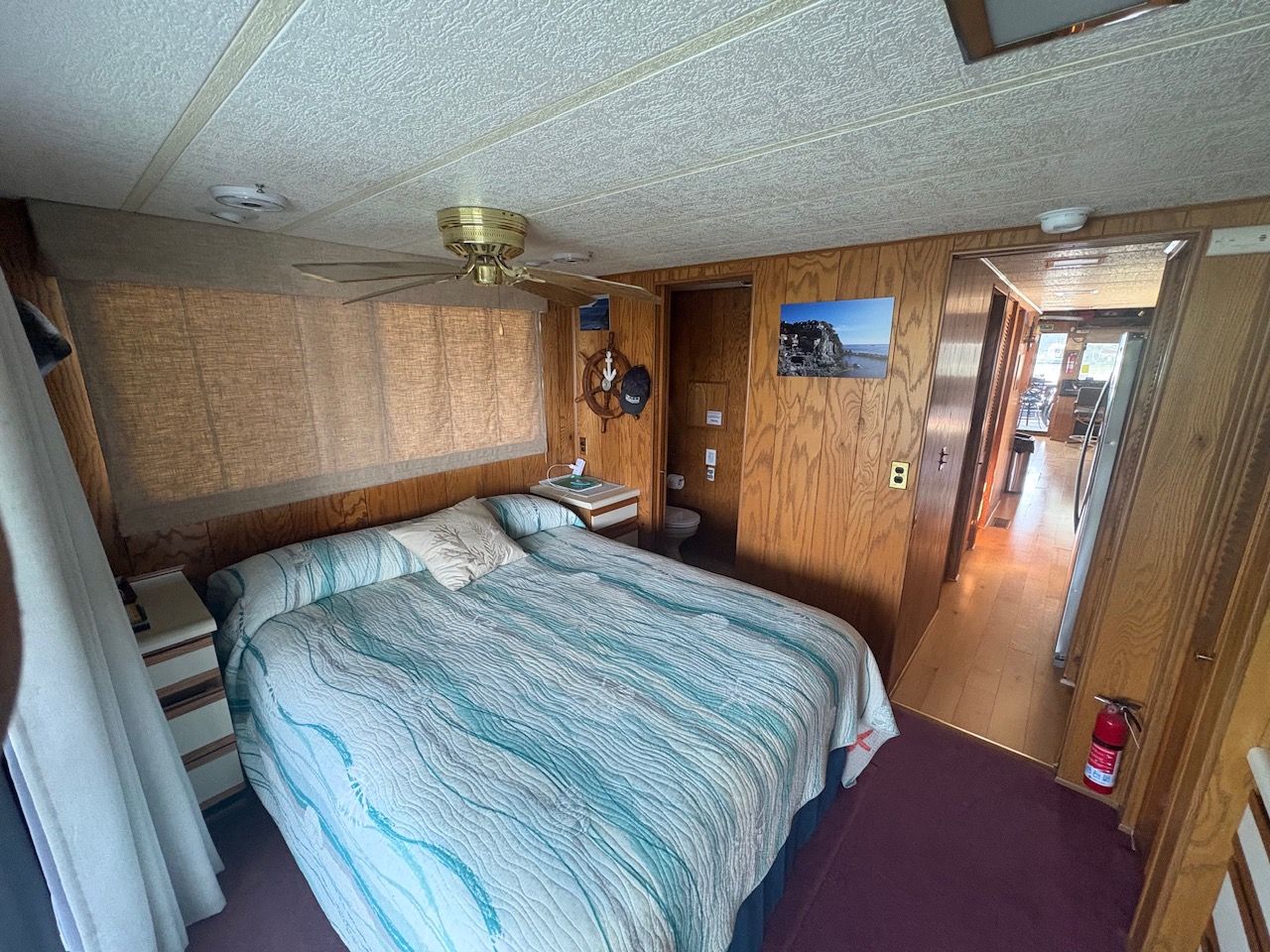 Interior of a Sumerset houseboat cabin with a double bed, wood paneling, and ceiling fan.