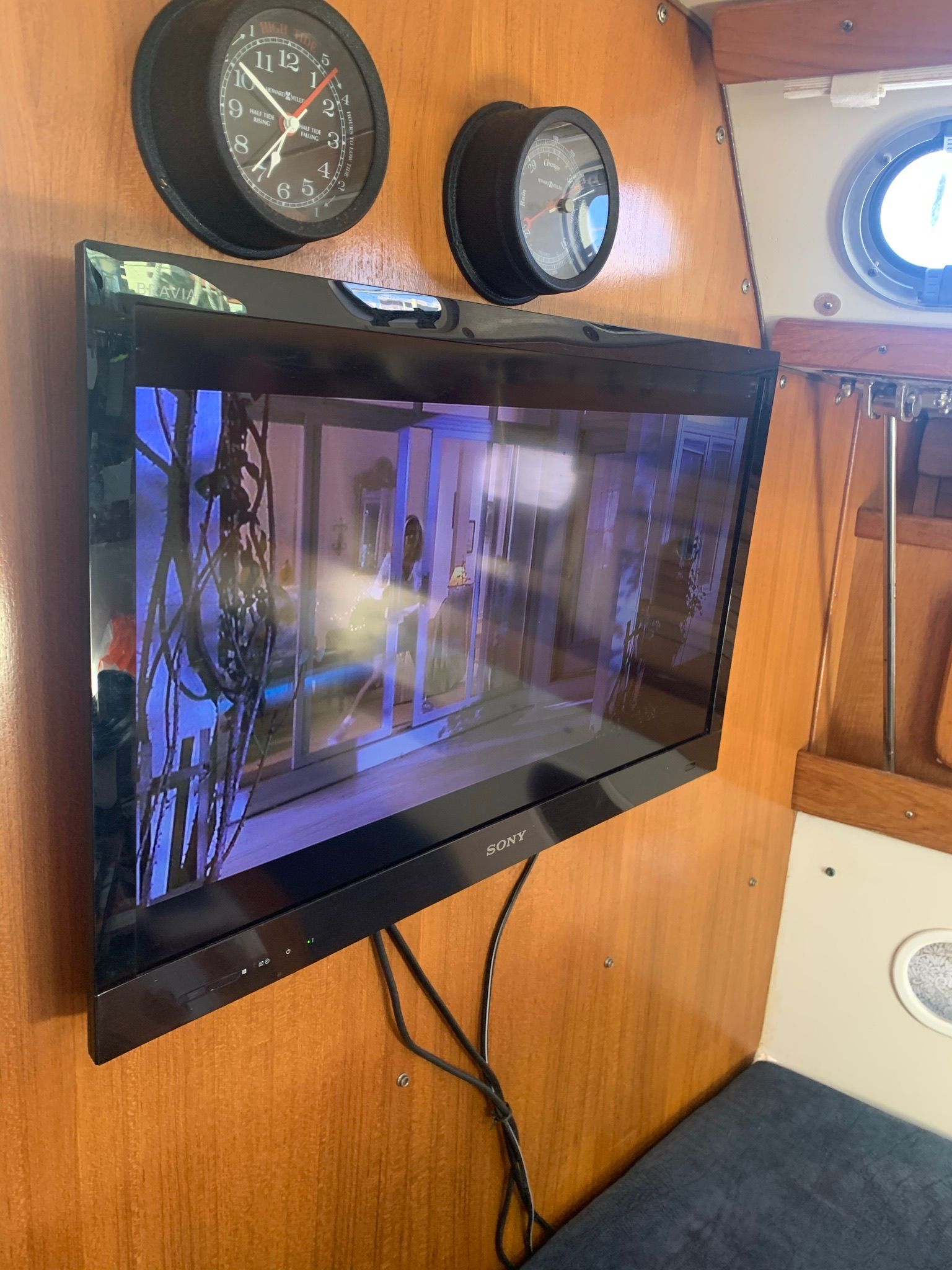 A TV is mounted on the wooden wall of a boat.