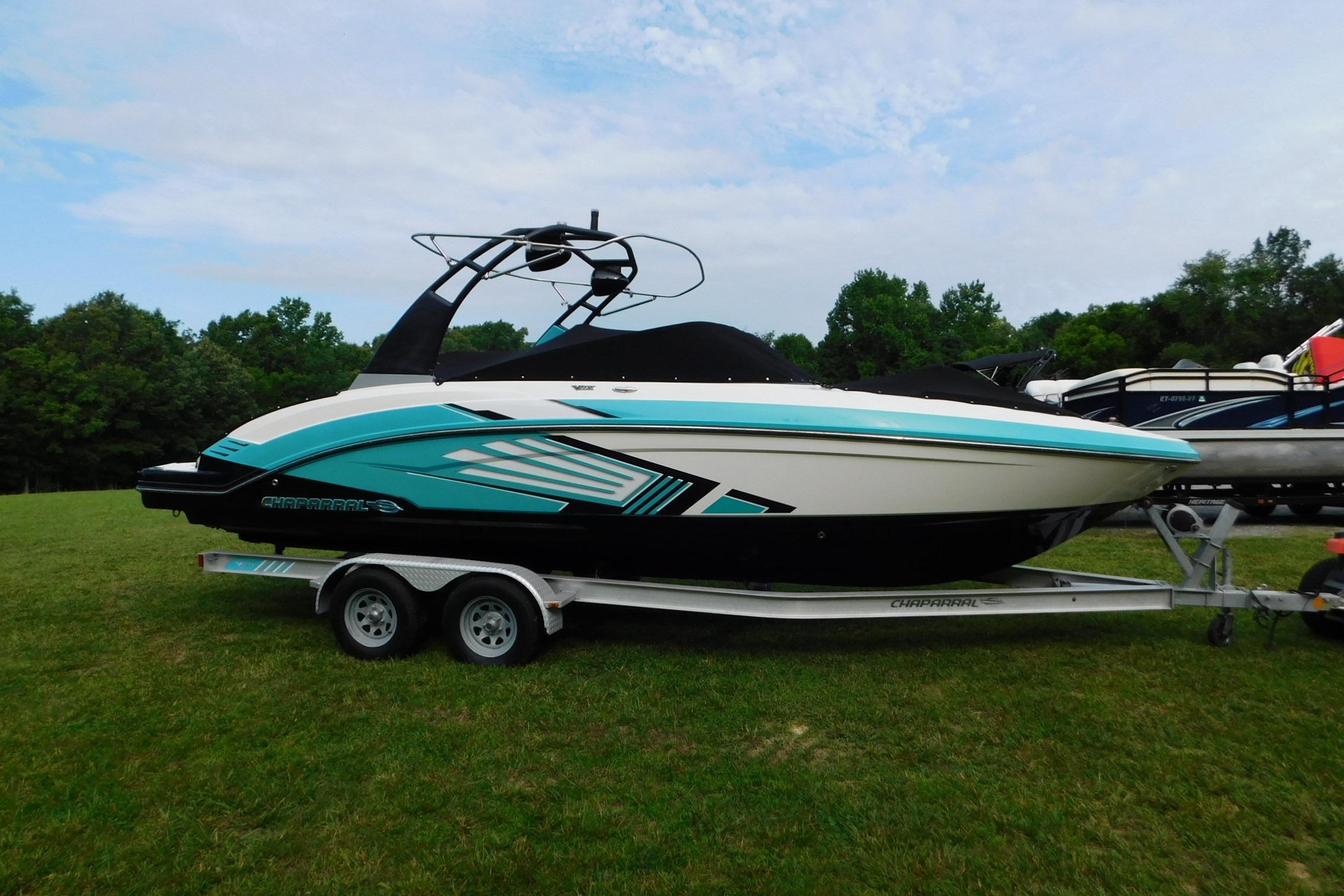 2016 CHAPPARRAL 243 boat on trailer, parked on grass with trees in background.