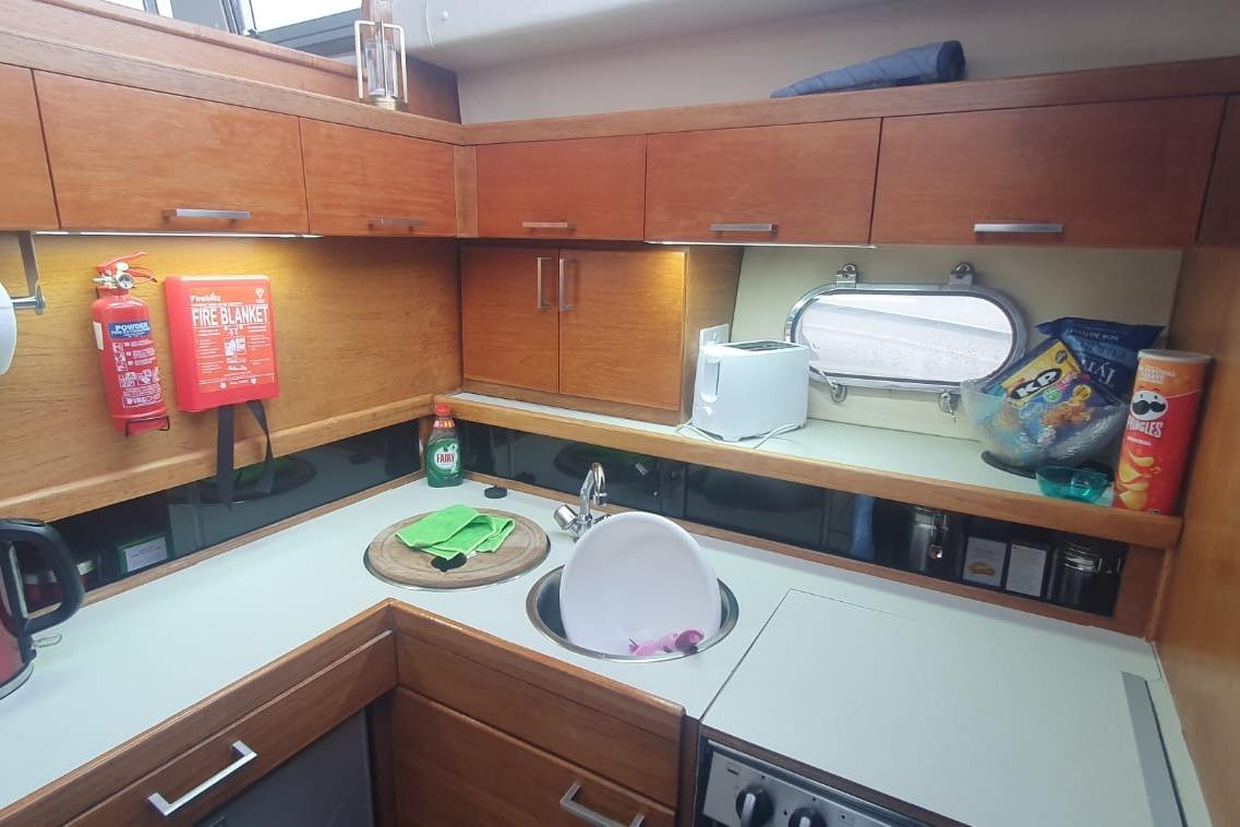 Compact kitchen in a 1989 Princess 35 yacht with wooden cabinets and modern appliances.