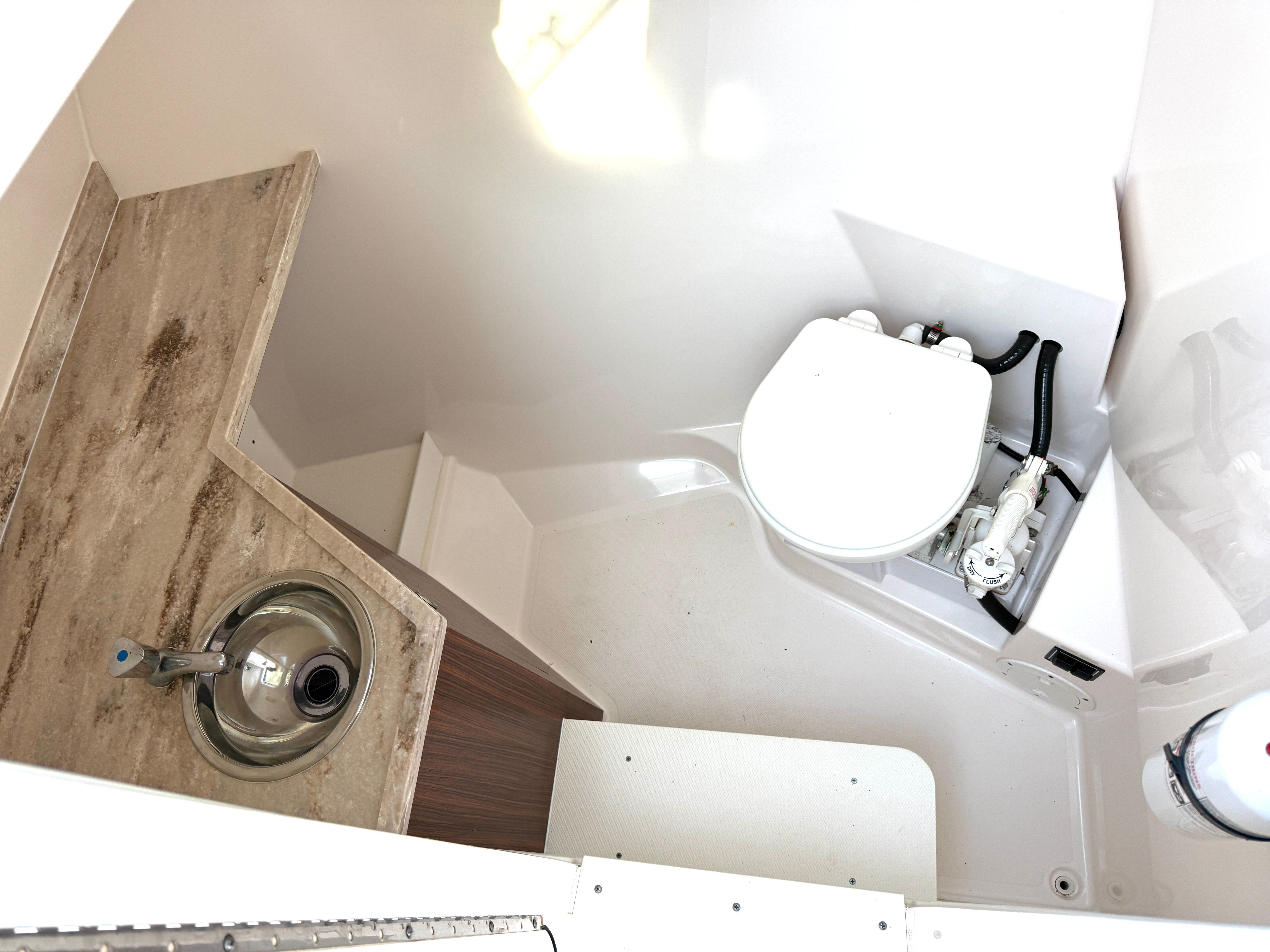 The image shows a clean, modern boat bathroom with a toilet and a sink.