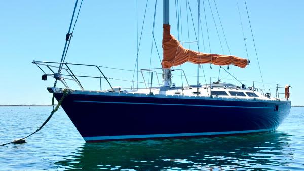 1983 O'Day 39 sailboat with orange sail cover on calm water.